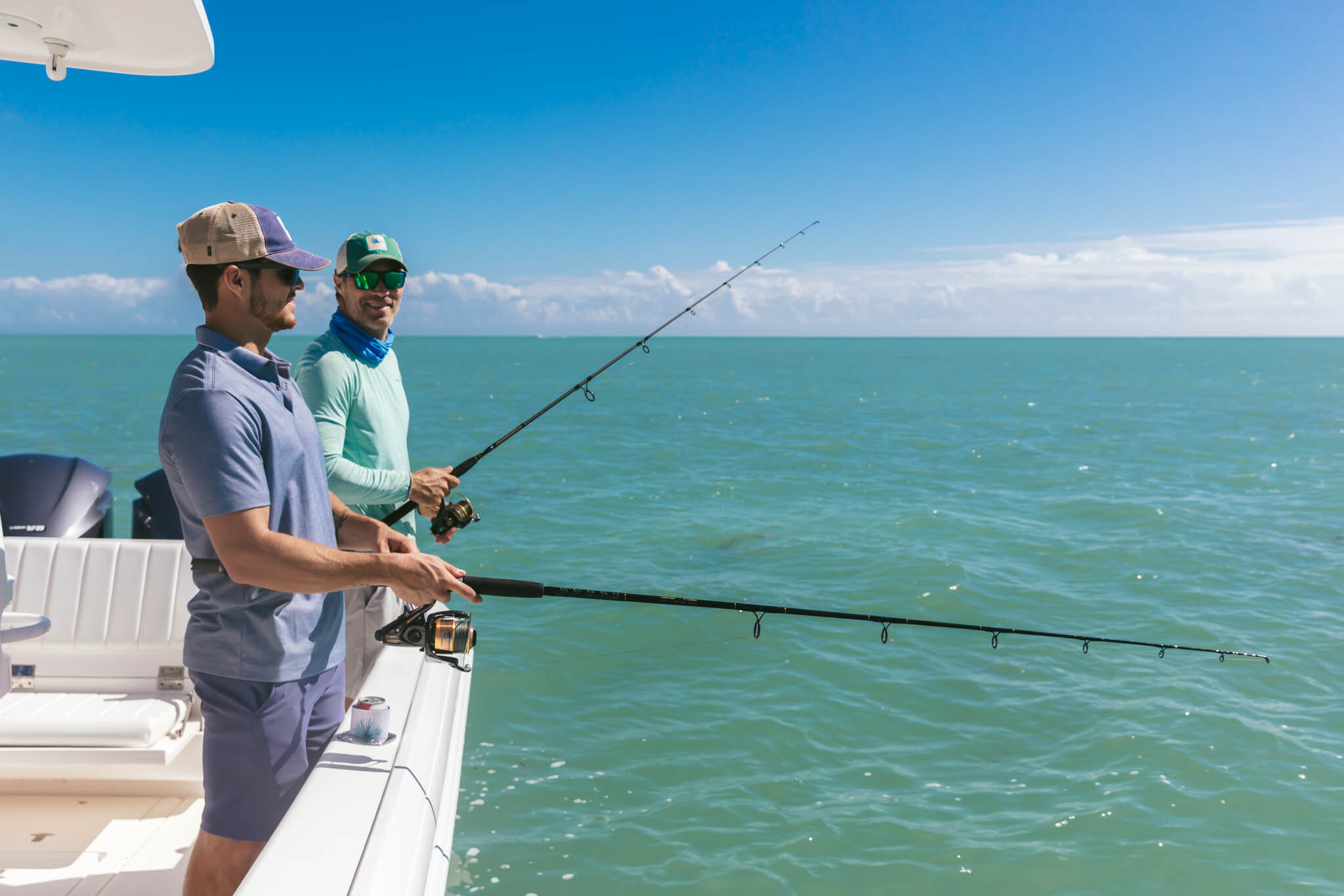  Two Men Fishing Off A Boat Into The Clear Waters Of The Atlantic Ocean By The Islands Of Islamorada In Florida. 
