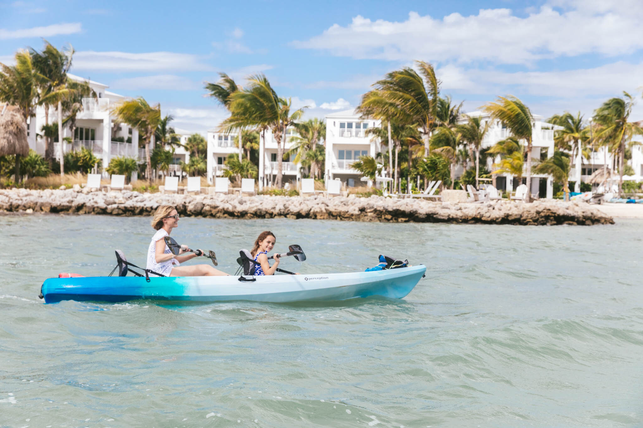  A Mother And Her Young Daughter Paddle In A Kayak In The Ocean Offshore The Islands Of Islamorada With The Resort’s Ocean View Villas In The Background. 