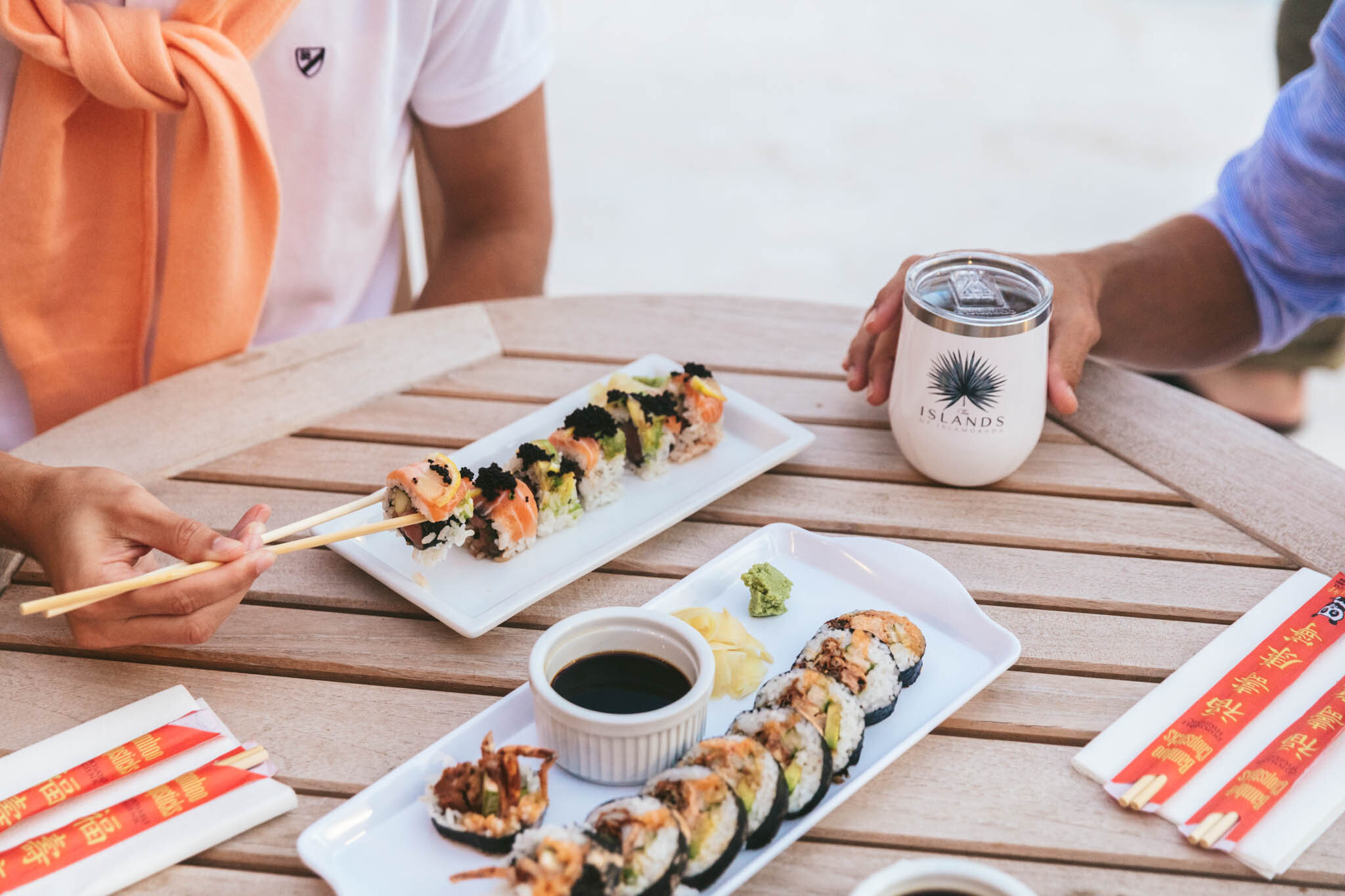  Plates of sushi with soy sauce, ginger, and wasabi on a table on The Islands of Islamorada’s private beach. 