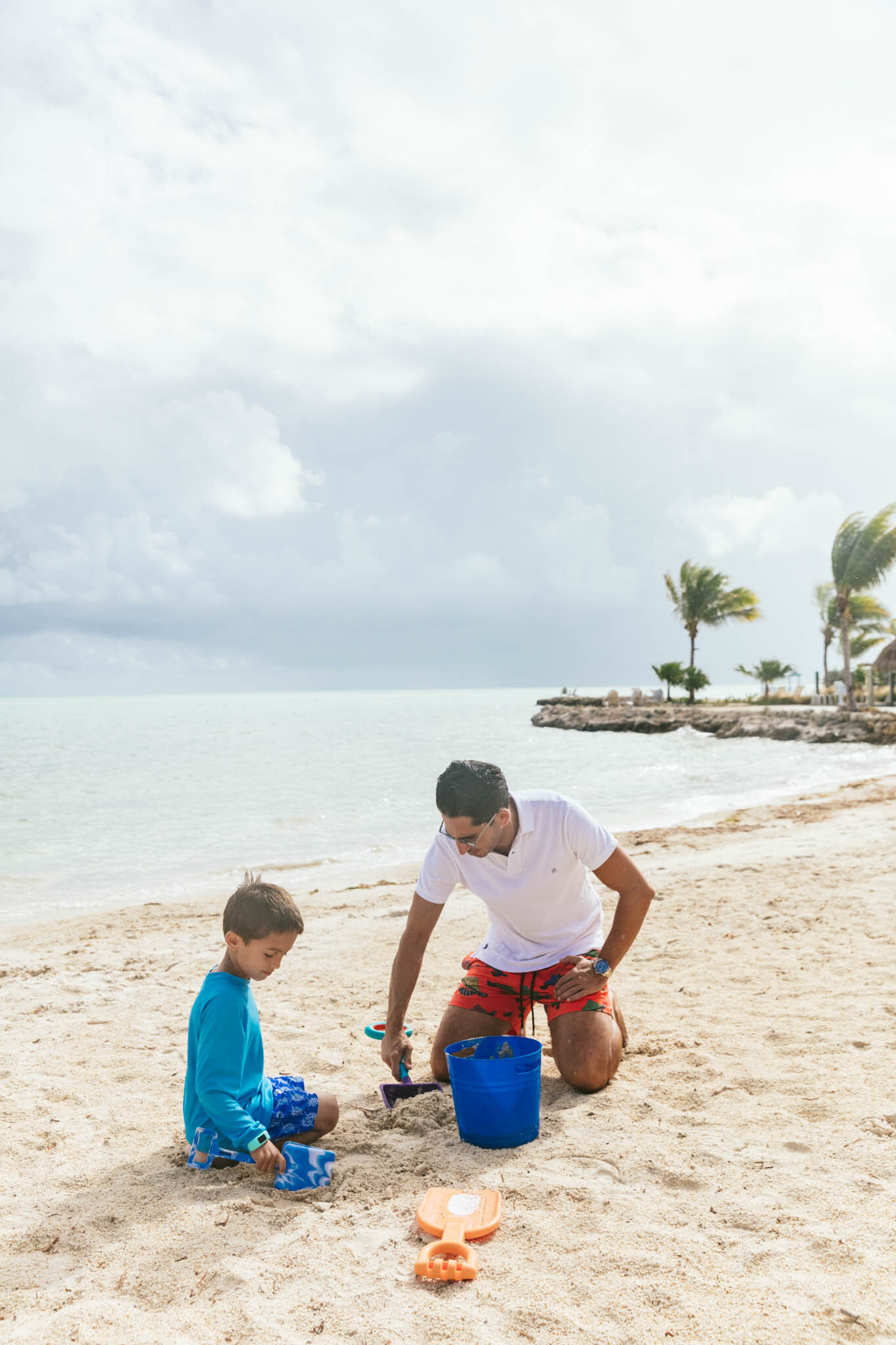  Father and young son playing in the sand with shovels and pails on The Islands of Islamorada’s private beach. 