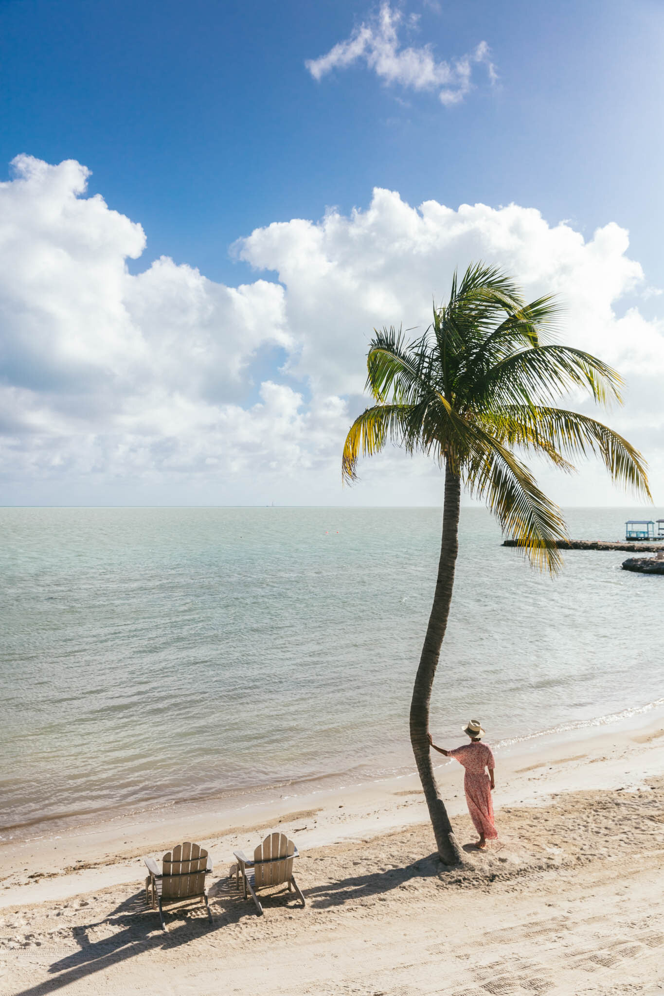  Woman standing under a palm tree on The Islands of Islamorada’s private beach, looking out on the Atlantic Ocean. 