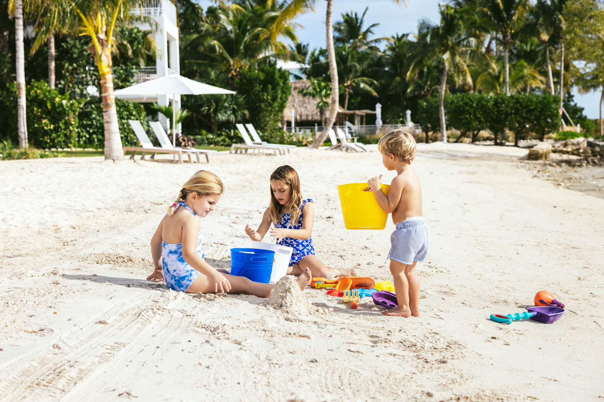  Three kids playing in the sand with shovels and pails on The Islands of Islamorada’s private beach. 