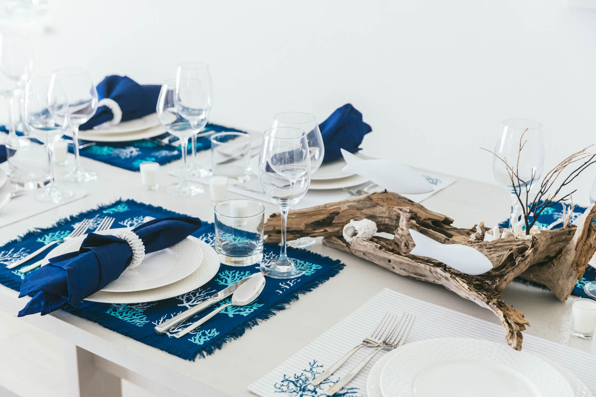  Dining area table set for a meal with ocean-themed table settings in an Islands waterfront villa. 