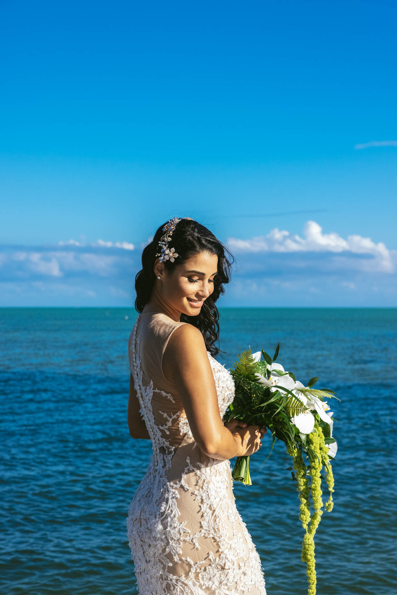  Bride holds a wedding bouquet on The Islands of Islamorada’s private beach with the crystal clear waters of the Atlantic Ocean as a backdrop. 