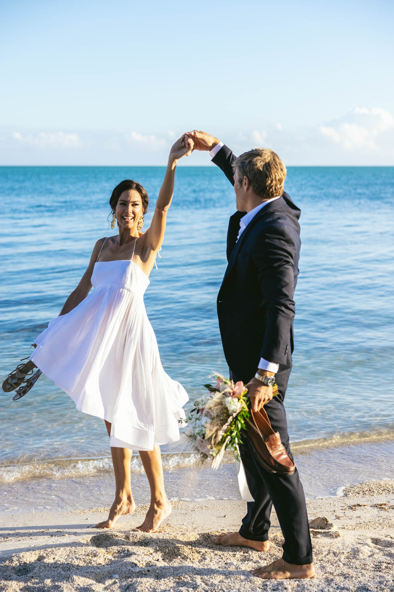  Groom twirls his bride while dancing on the sand on The Islands of Islamorada’s private beach with the Atlantic Ocean in the background. 