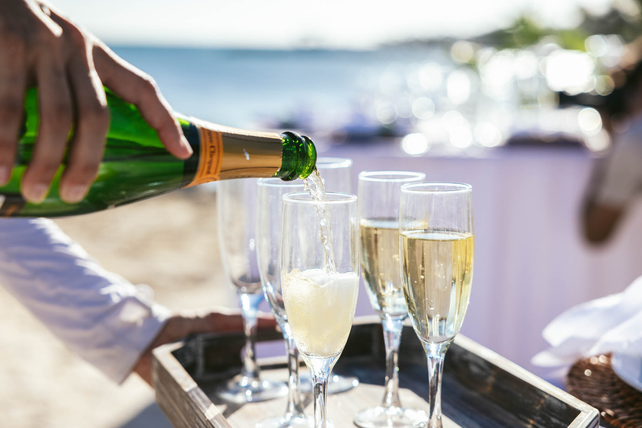  Champagne being poured into glasses at a wedding reception on The Islands of Islamorada’s private beach. 