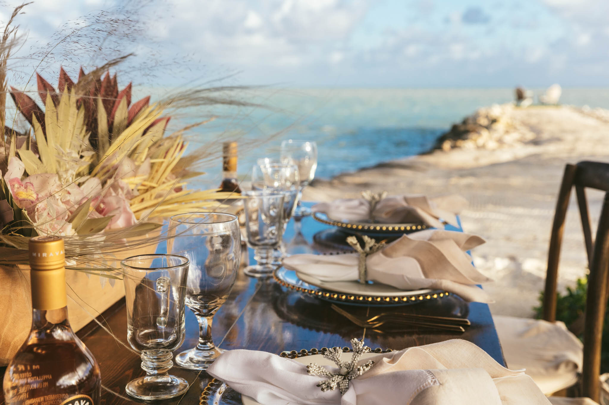  Table set for a wedding reception on The Islands of Islamorada’s private beach with the jetty looking out onto the Atlantic Ocean as a backdrop. 