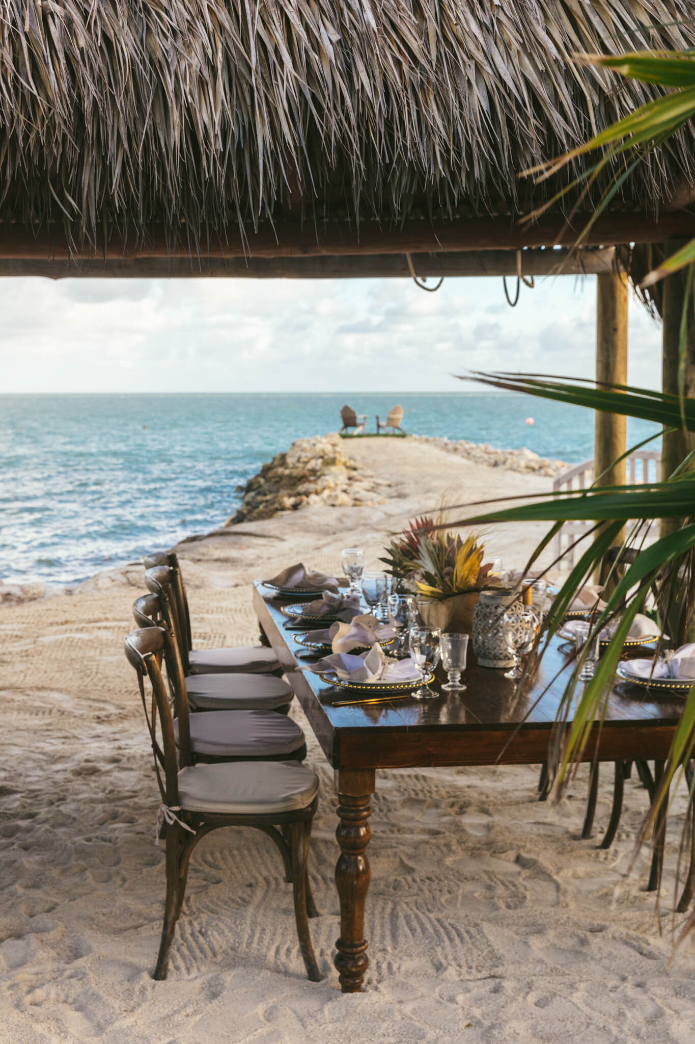  Table set for a wedding reception under The Islands of Islamorada’s tiki bar hut on the beach. 