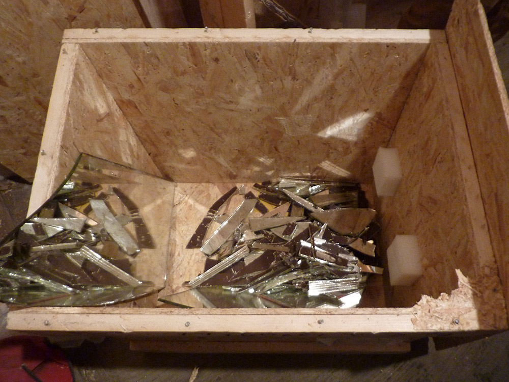 Shattered 3/8” thick beveled mirror glass at the bottom of the shipping crate