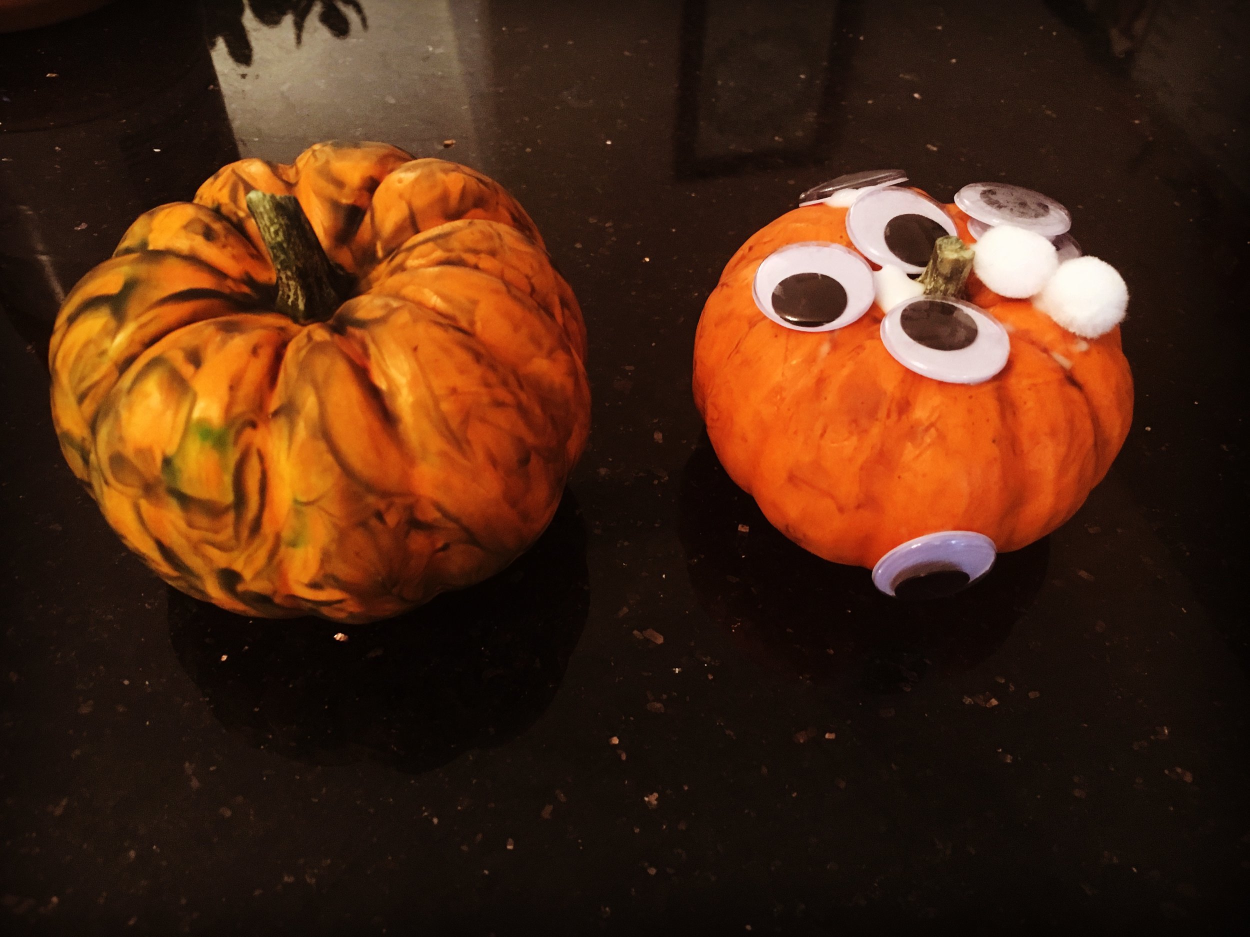Image: two mini pumpkins decorated by toddlers
