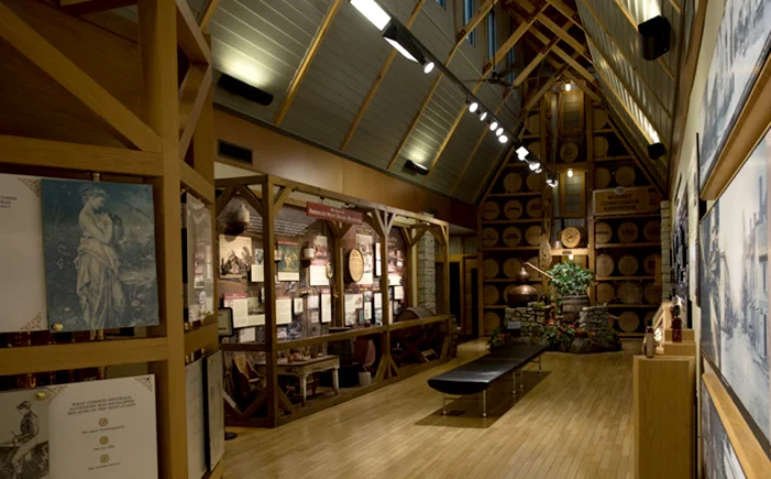 Inside the "Bourbon Heritage Center" is a wall at the end of the hall with a still in front of it at over 30 Barrel Heads with different brands of bourbon made by Heaven Hill burnt into them.