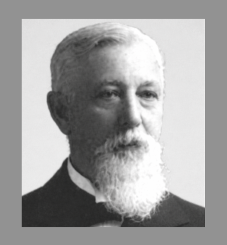 Black and white portrait of an older man with a beard and mustache in formal attire