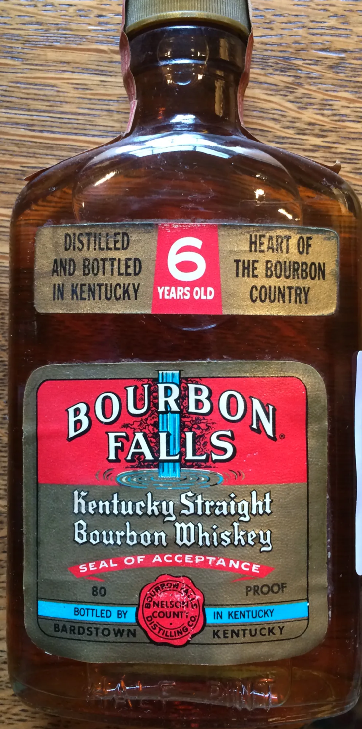 A bottle of Bourbon Falls Kentucky Straight Bourbon Whiskey, aged 6 years, with a label indicating it is distilled and bottled in Kentucky, and marked as proof. The label features a red and gold design with a seal of acceptance.