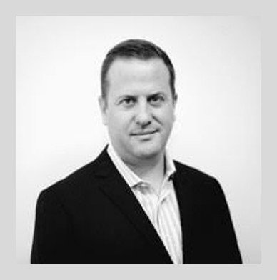 Black and white portrait of a man in a suit, smiling slightly