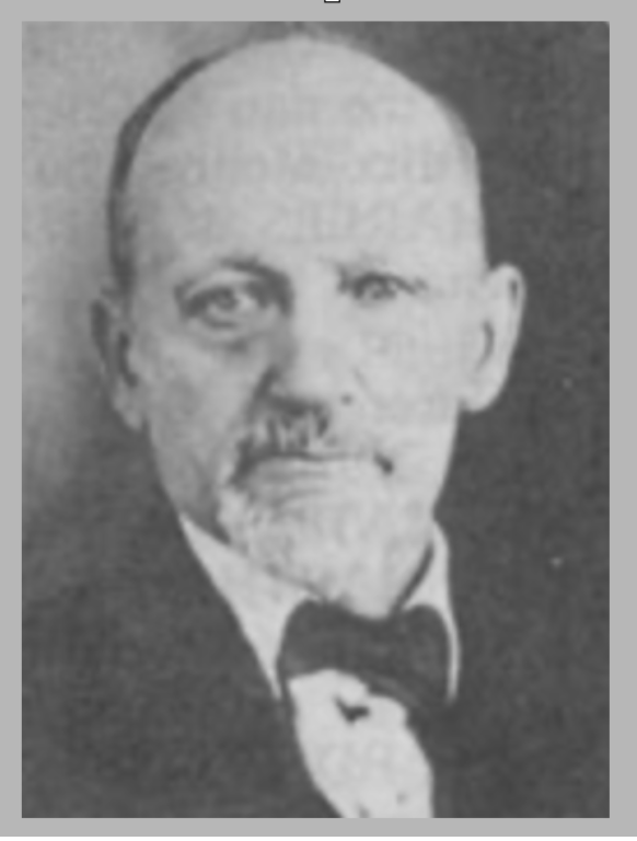 Black and white photograph of a man with a mustache and beard, dressed in formal attire with a bow tie.