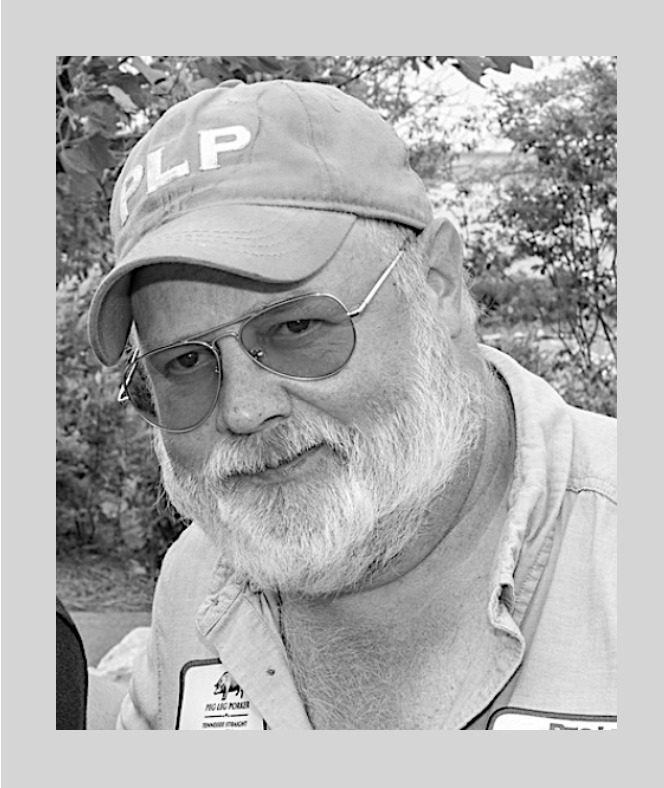 A black and white photo of an older man with a beard wearing sunglasses, a cap with the letters "PLP," and a shirt with patches, outdoors with trees in the background.