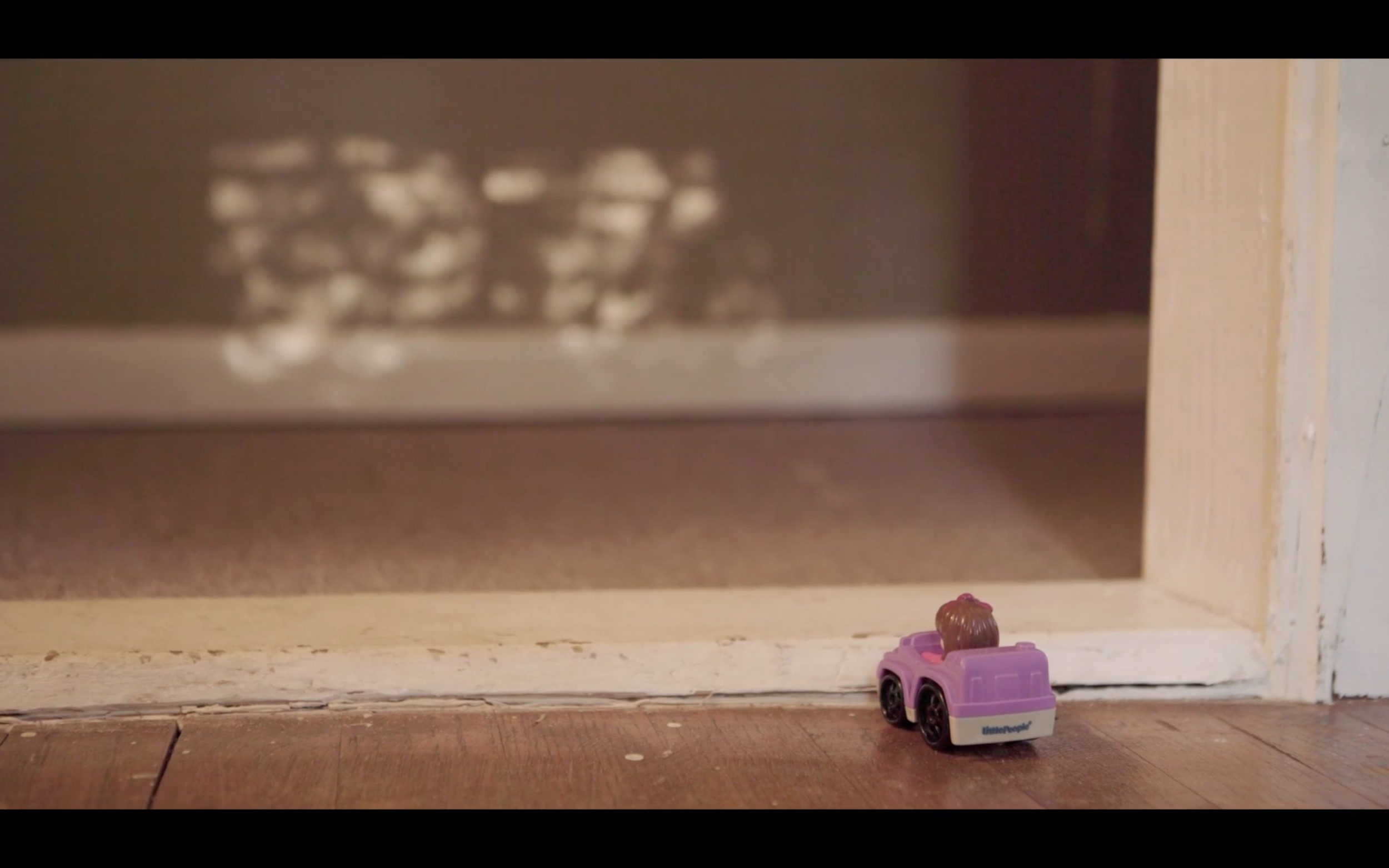 A small pink toy car sits against a door jam, blocking its forward motion