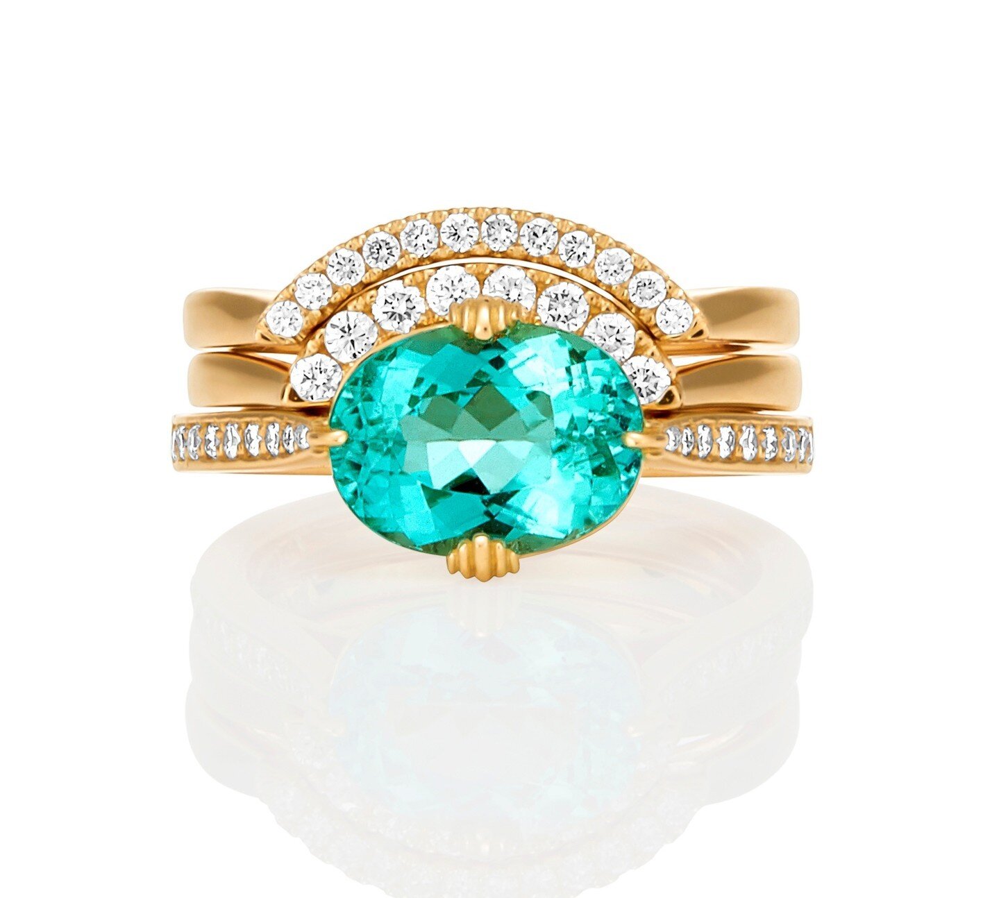 This ring was made to symbolize both the beauty of the Ocean and Surf and New York City. The center stone is an Oval-cut Paraiba Tourmaline from Brazil. Its colour is found in no other gemstone and evokes the stunning colours of pristine ocean water.