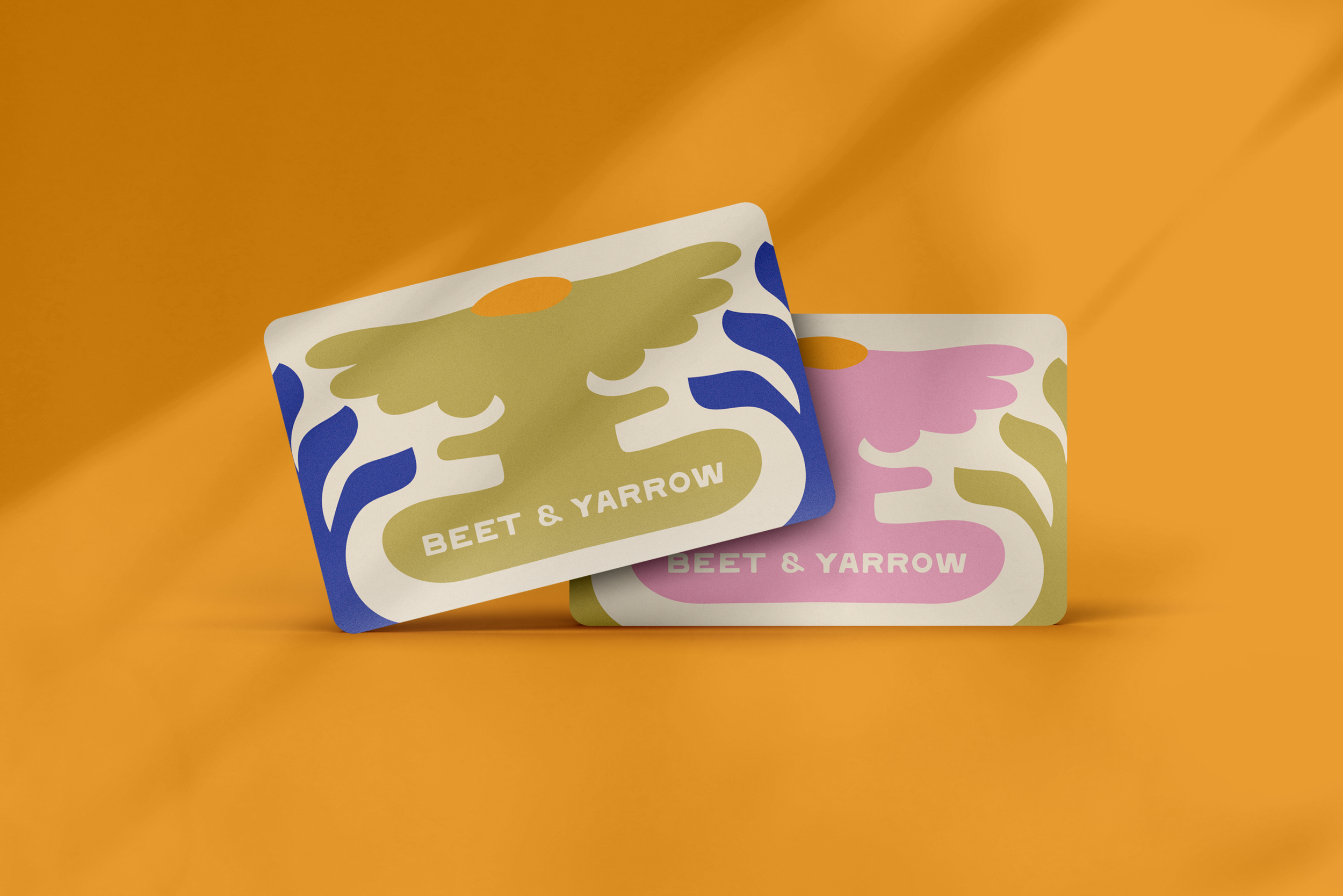 Two Giftcards with alternating floral designs one in green and one in pink overlayed a yellow gold background