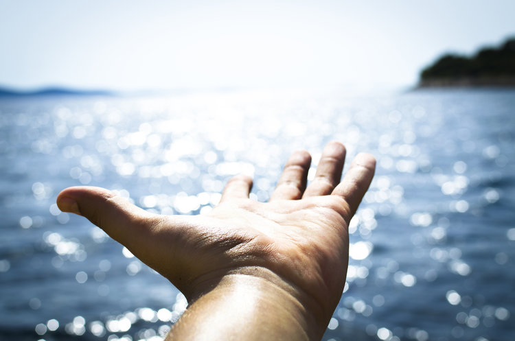 Hand outstretched over the ocean