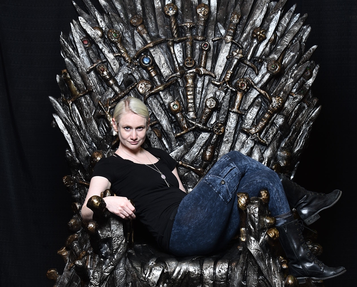 Justine mastin sits on the IRON THONE FROM GAME OF THRONES.