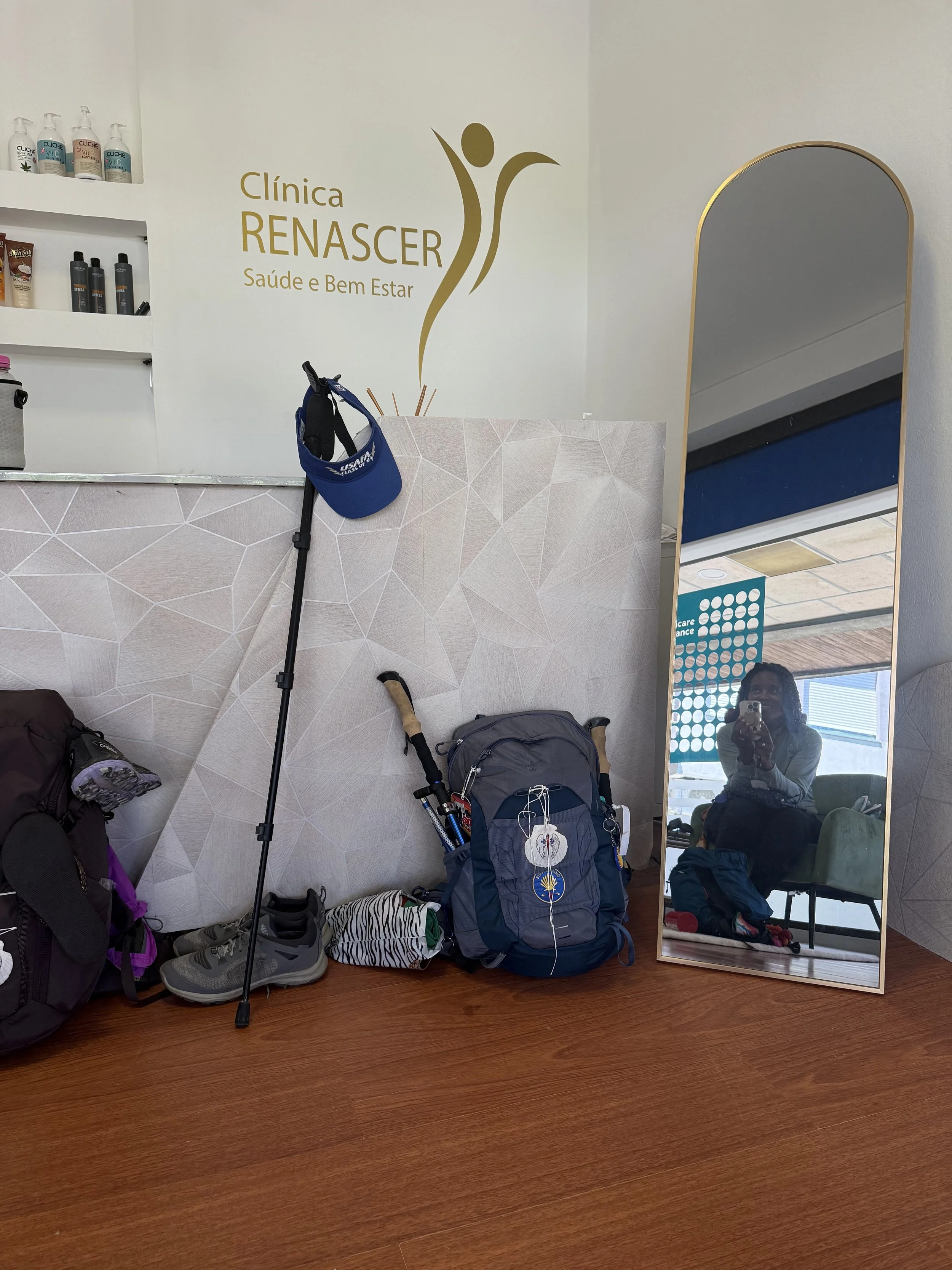 several backpacks and hiking poles placed on the floor under a "clinic renascent" sign.