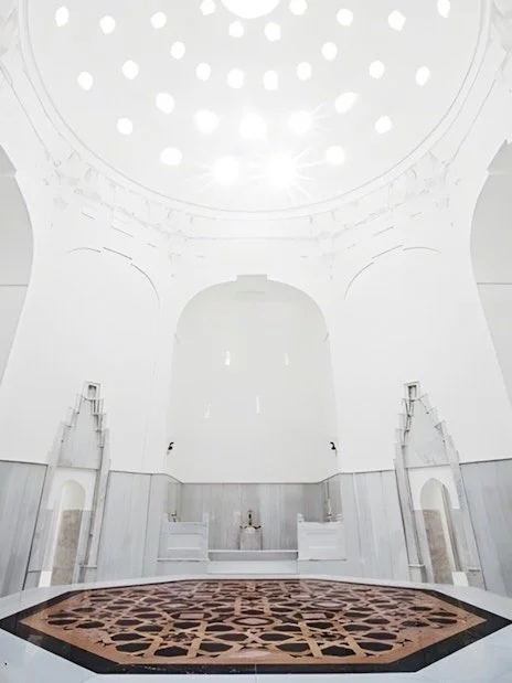 rotunda with pentagon shapes emitting light onto the tiled floor of a hamam.