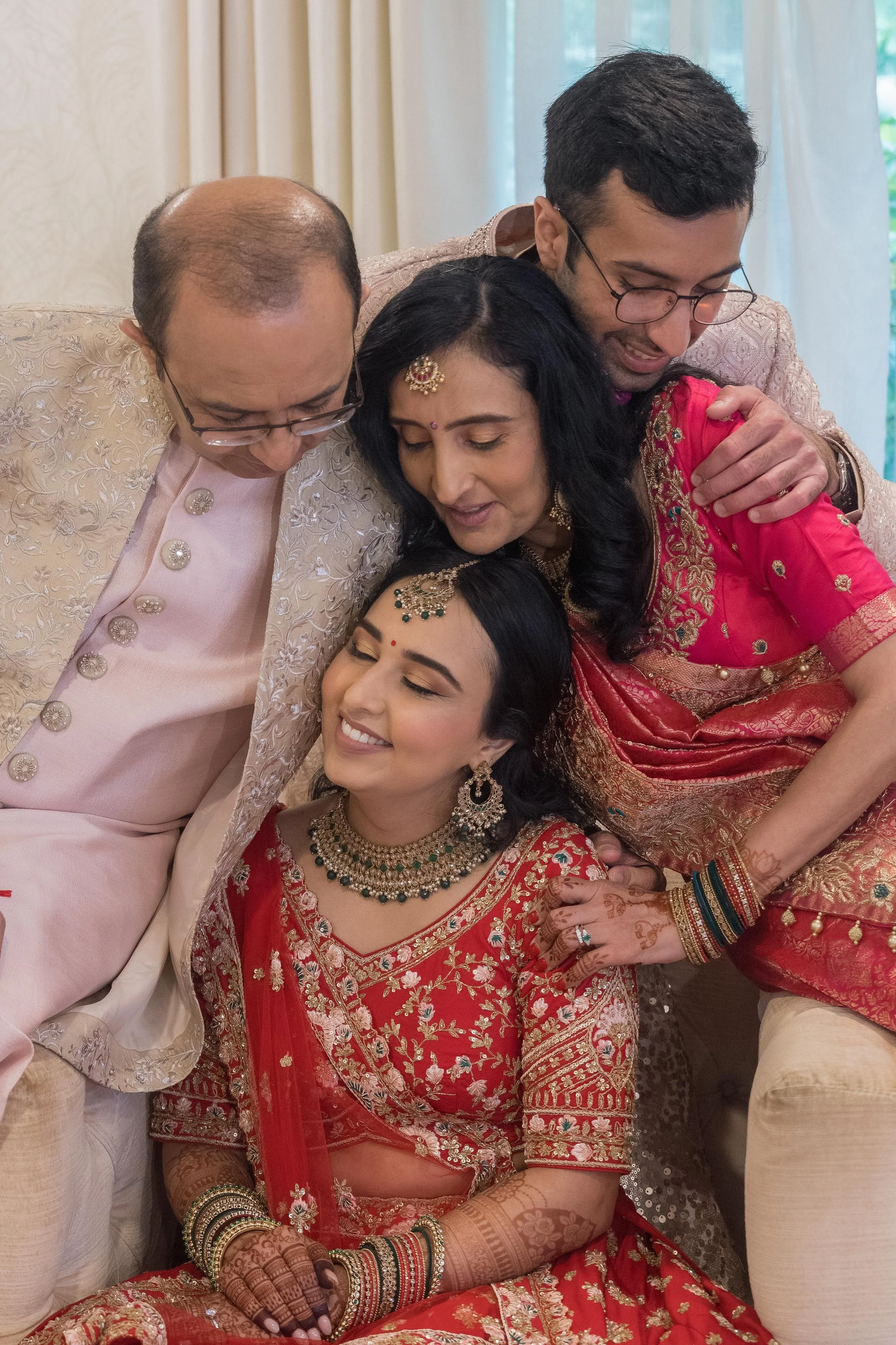 Family members dressed in traditional Indian attire embracing during a celebration.