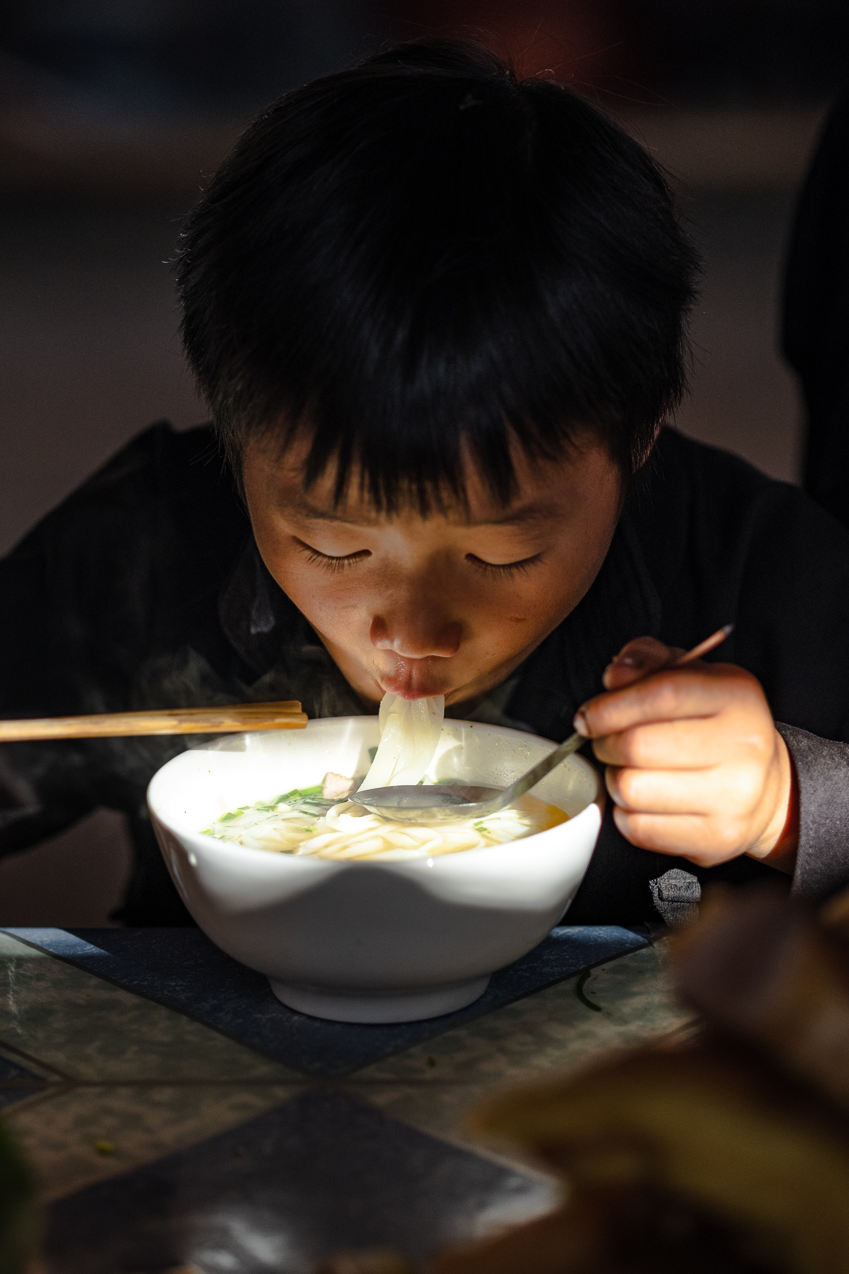  A boy enjoying his pho noodles in Dong van market in Vietnam. 
