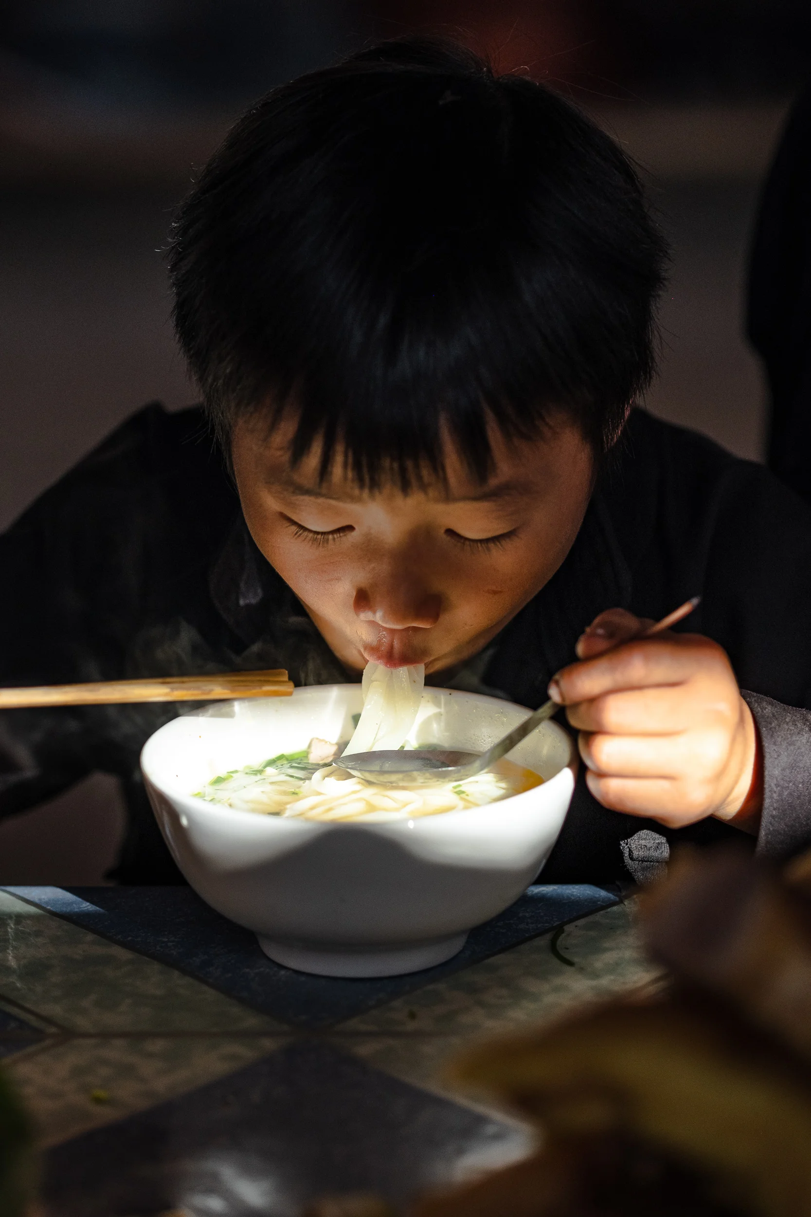 A boy enjoying his pho noodles in Dong van market in Vietnam.