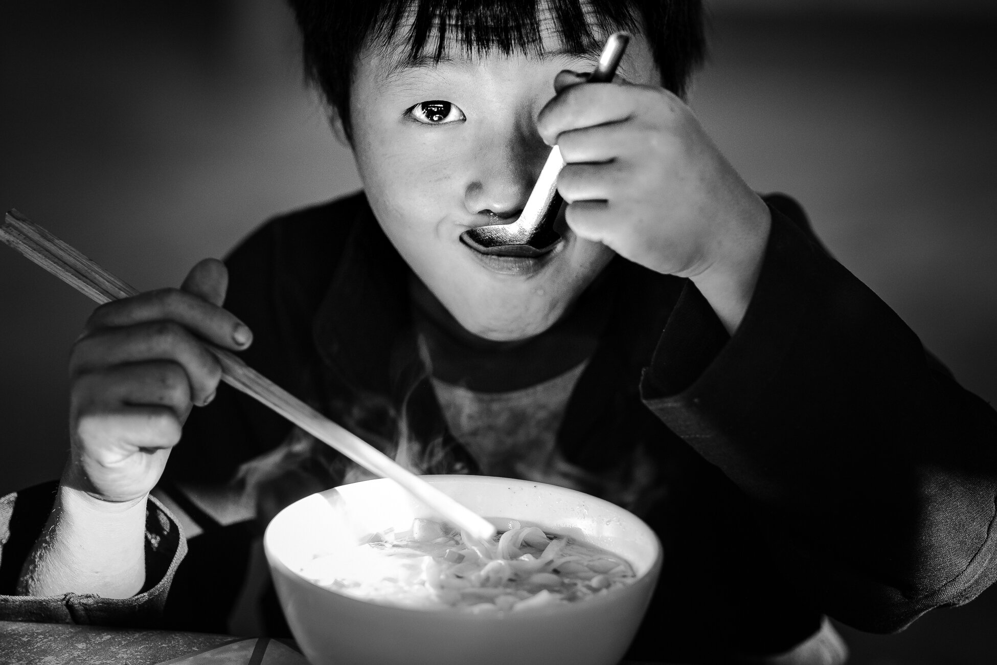 A young boy having pho noodles in Dong van market in northern vi