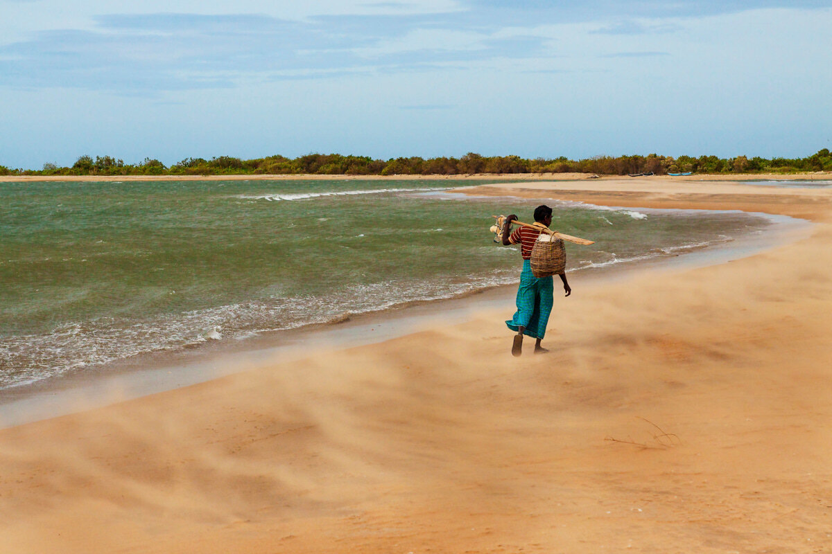  A fisherman walking at a beach through a small sand storm - Sri Lanka 