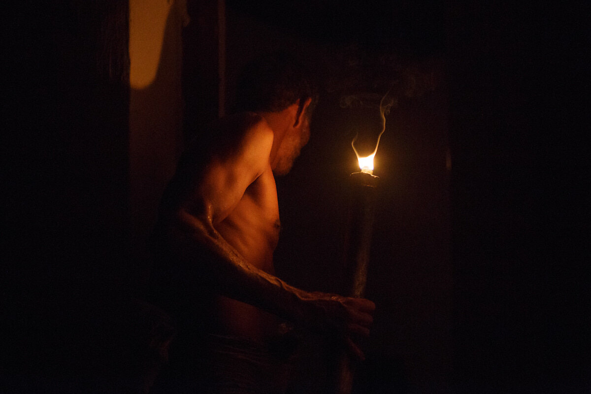 A villager carries a fire torch into the darkness