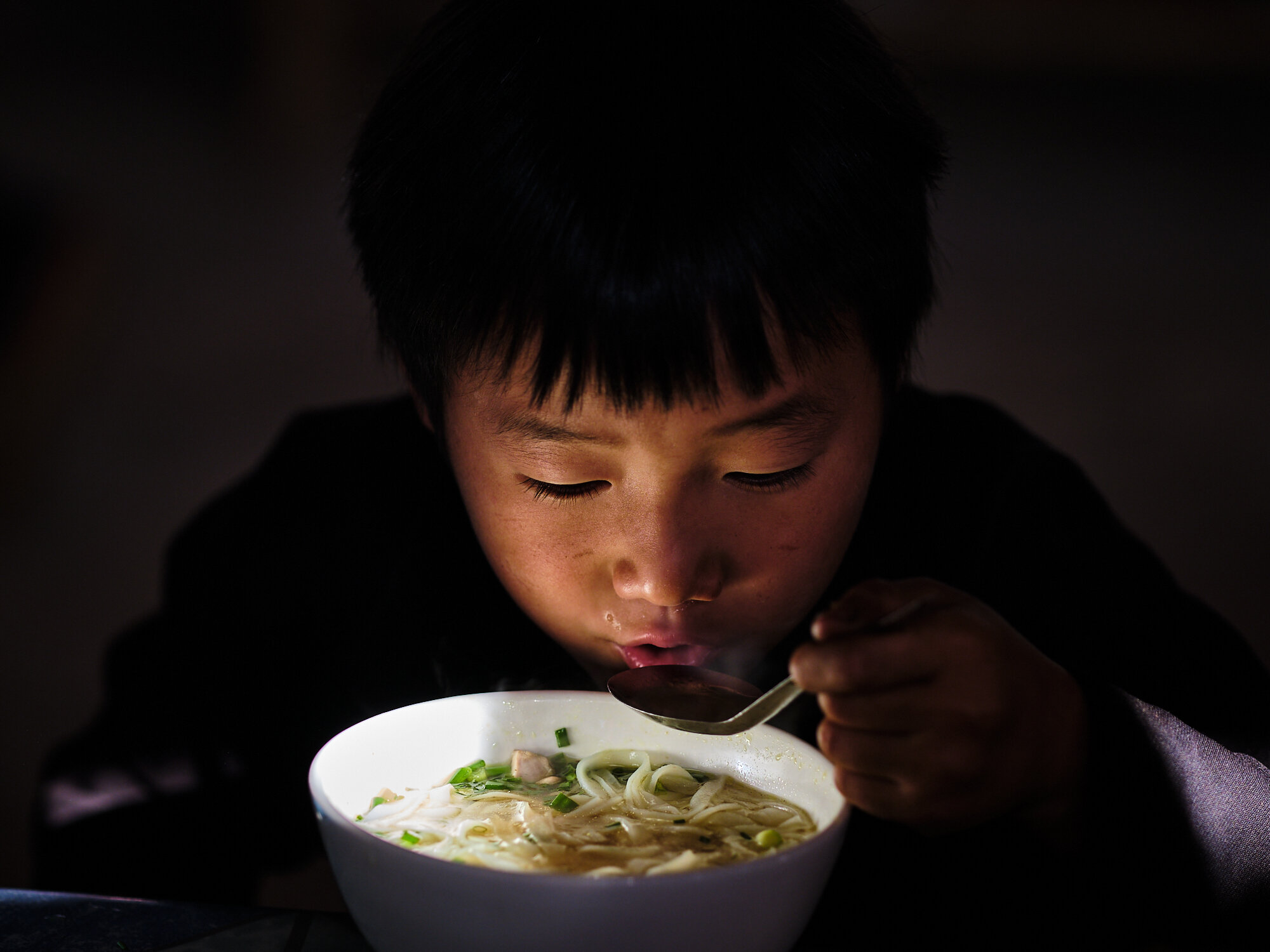  A young boy enjoying the pho nodle soup. 