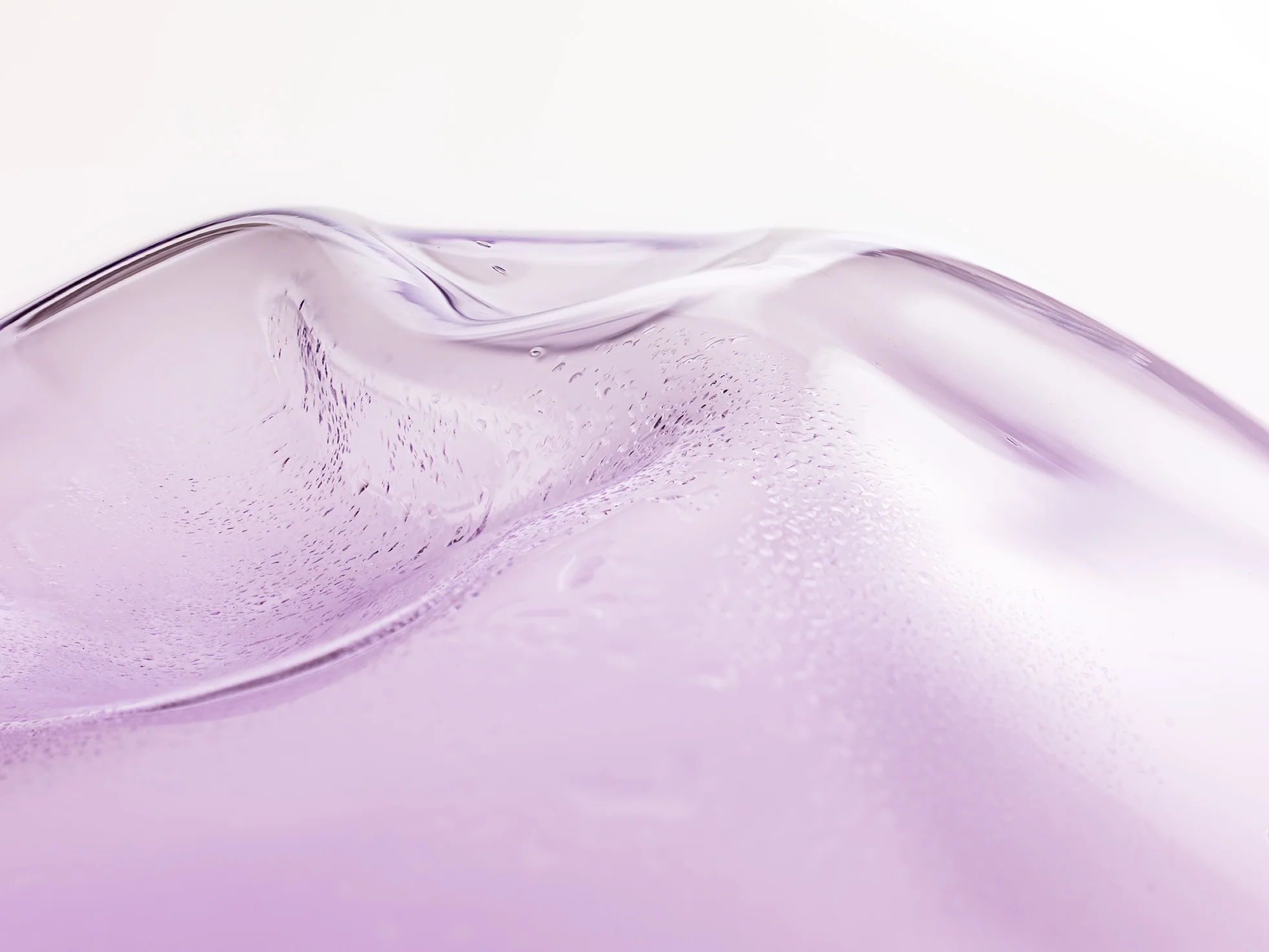 Close-up of a smooth, purple-tinted, abstract glass surface with gentle curves and subtle reflections.