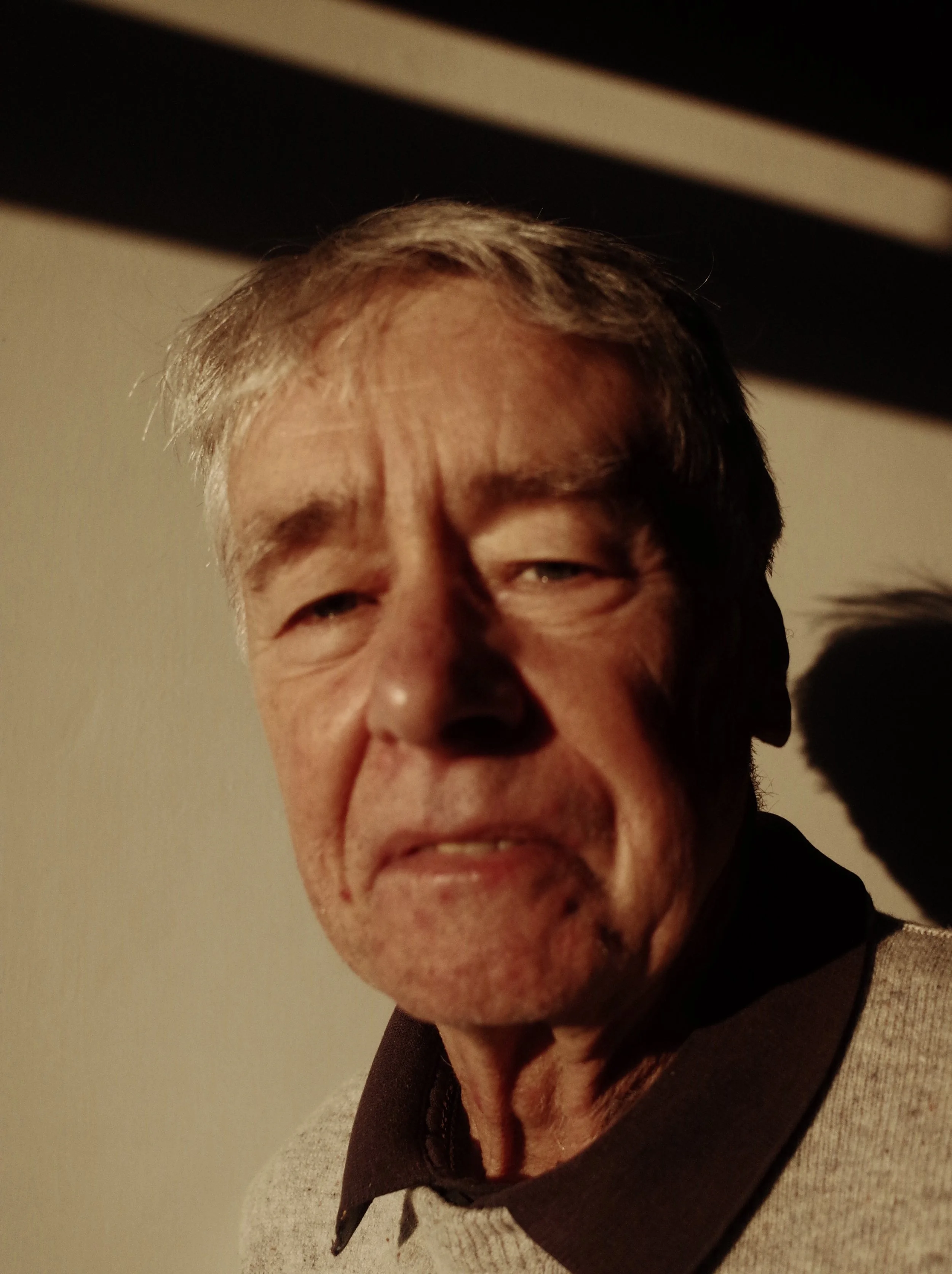 Close-up of an older man with gray hair making a grimacing expression.