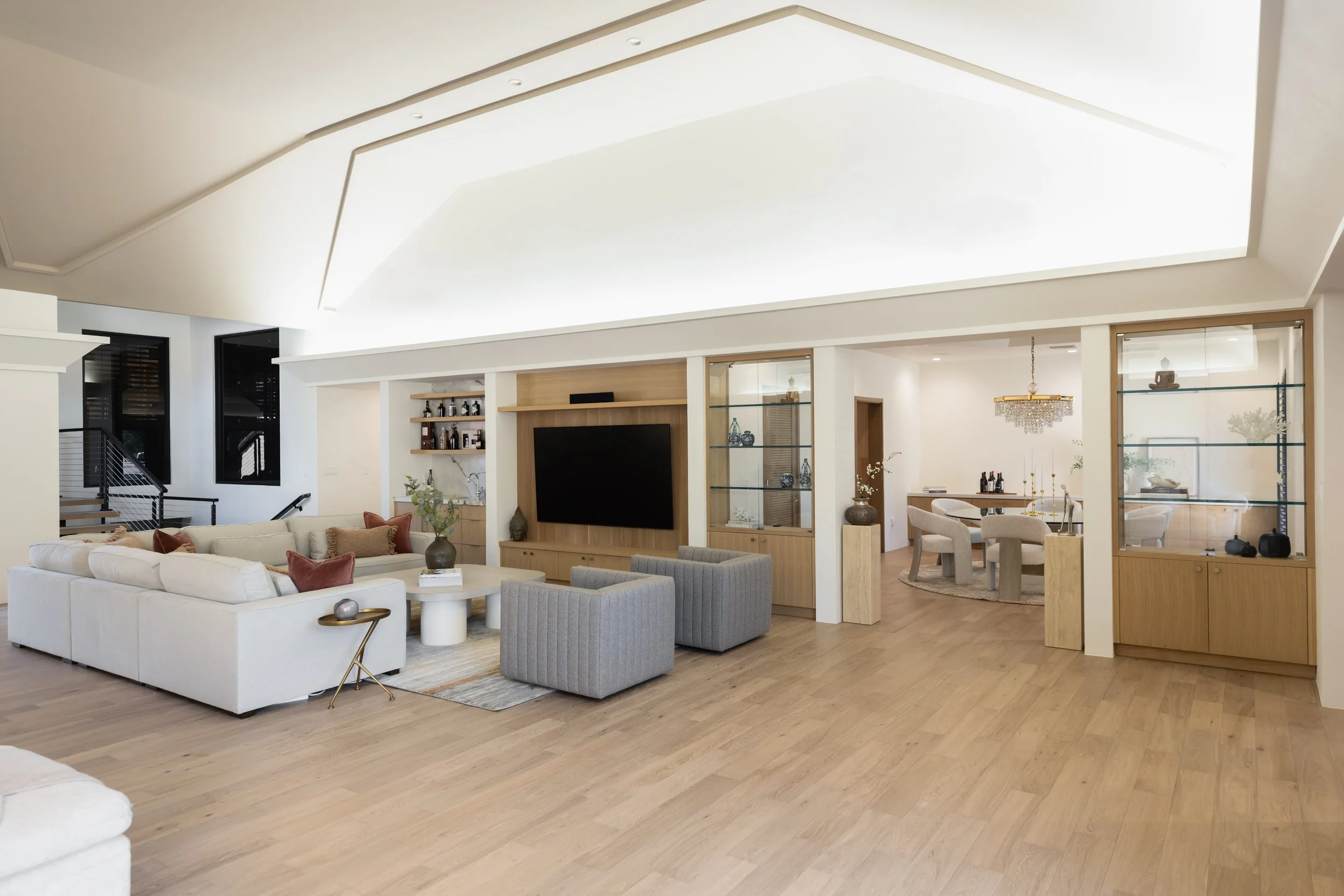 Warm modern living room with soft neutral furnishings, custom cabinetry and views into the adjoining spaces
