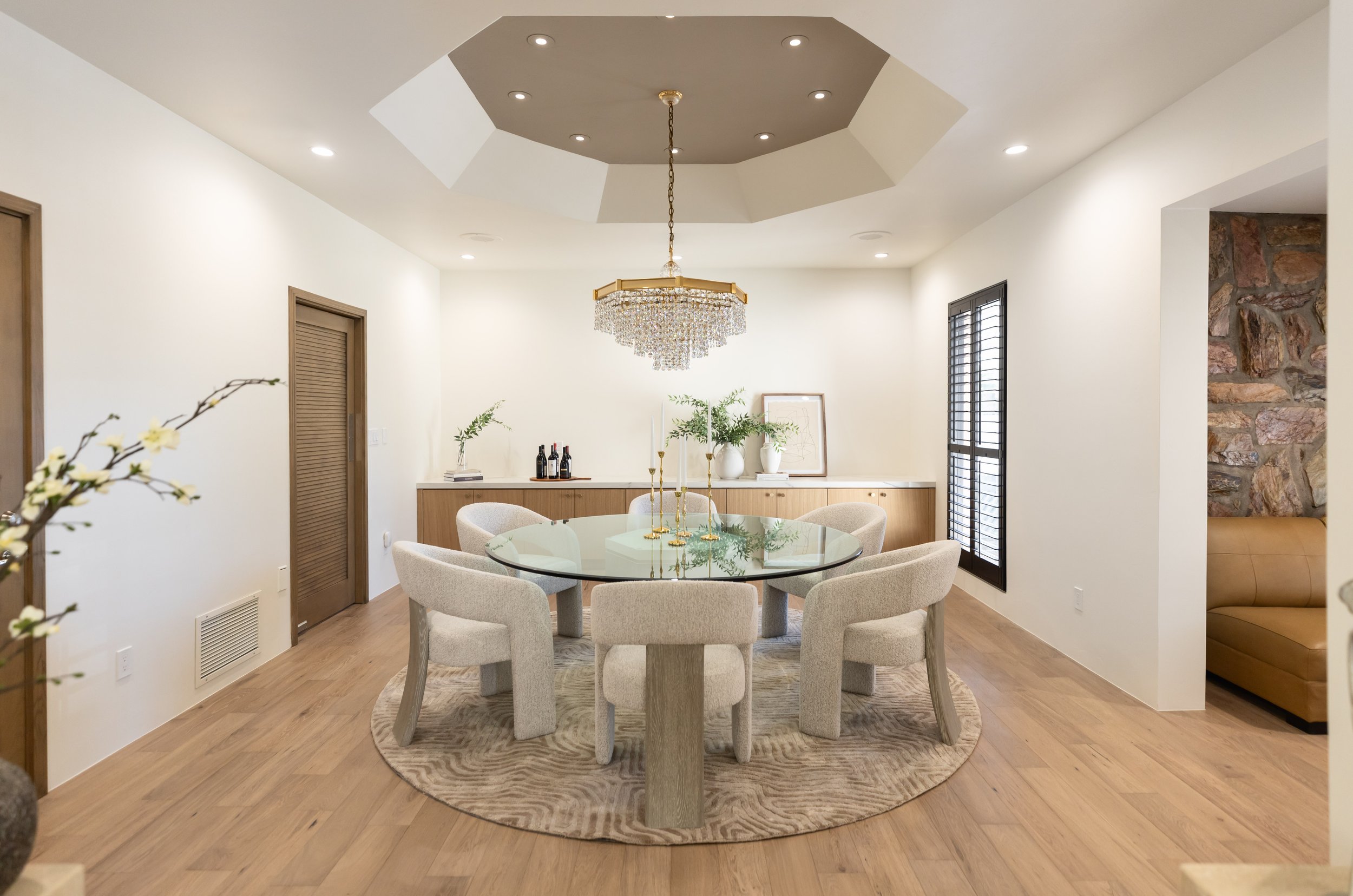 Warm modern dining room with custom wood cabinetry, layered furnishings and architectural ceiling detail