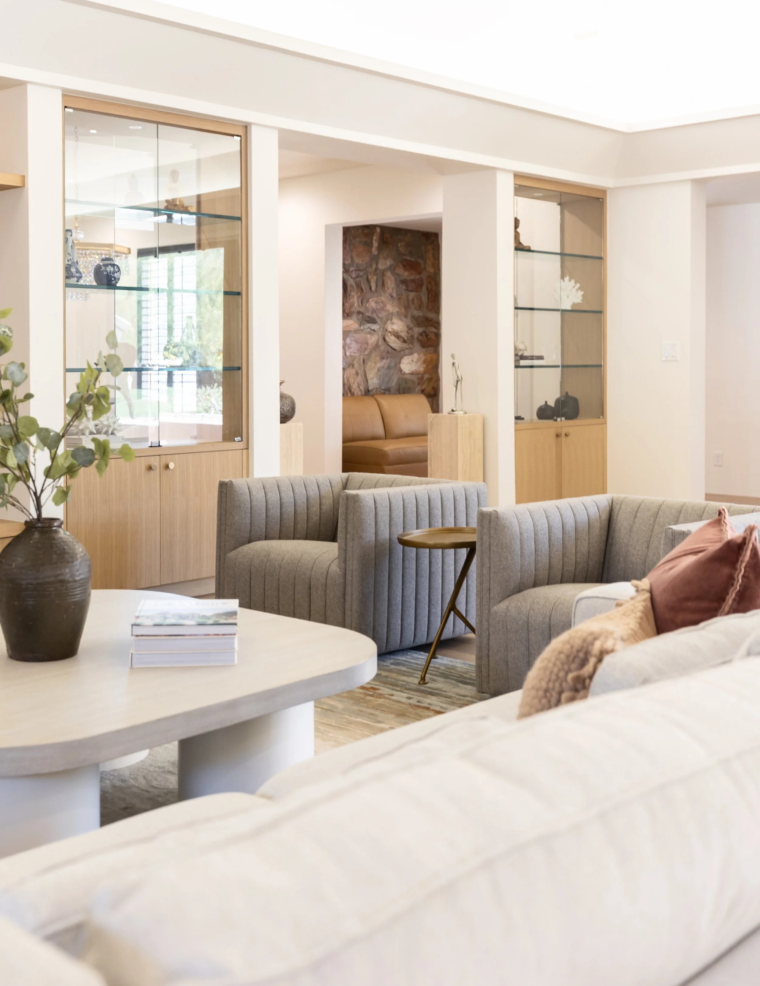 Layered neutral living room furnishings with sculptural tables and integrated custom cabinetry