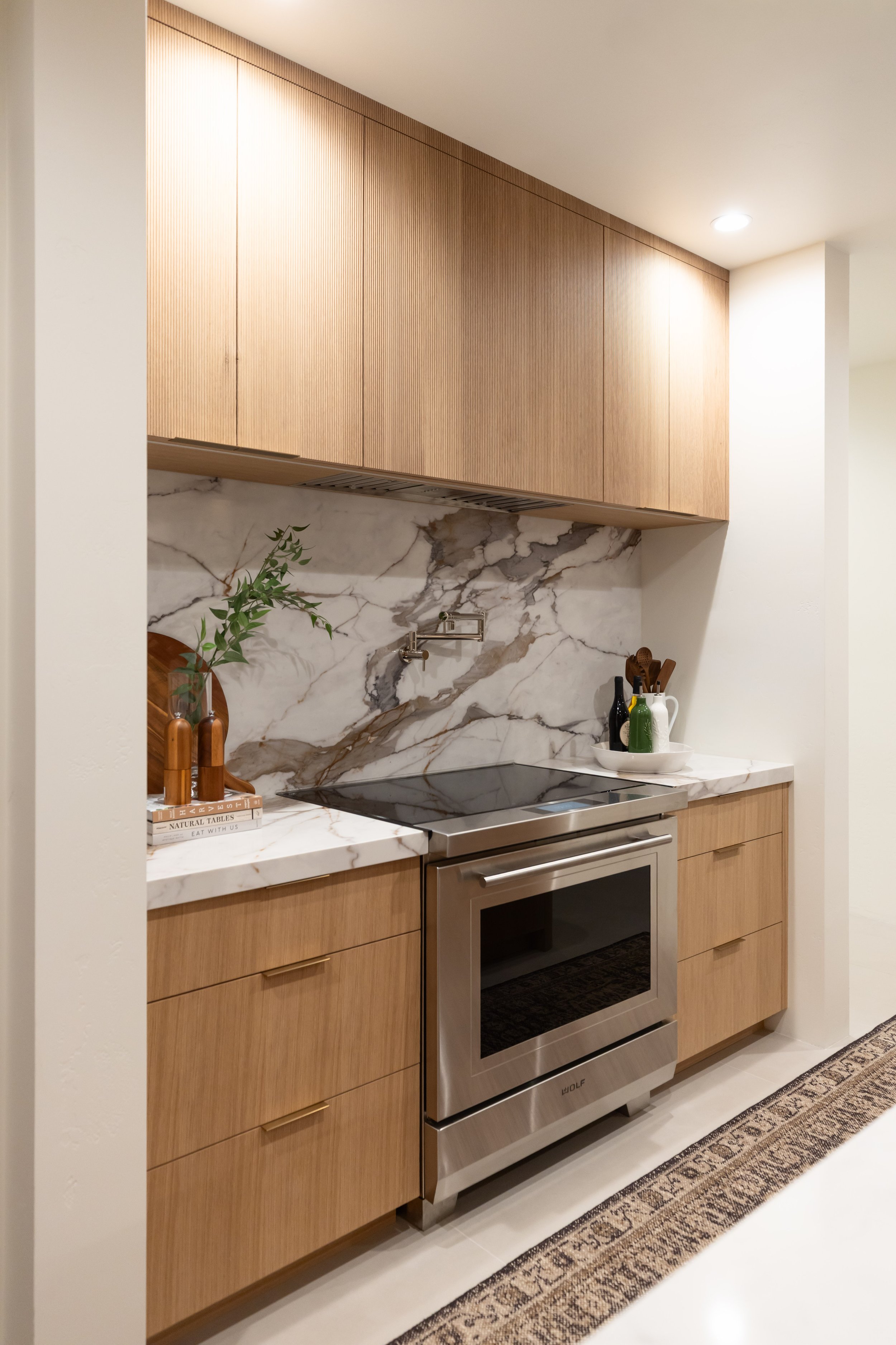 Custom wood kitchen cabinetry with dramatic natural stone backsplash and streamlined appliances