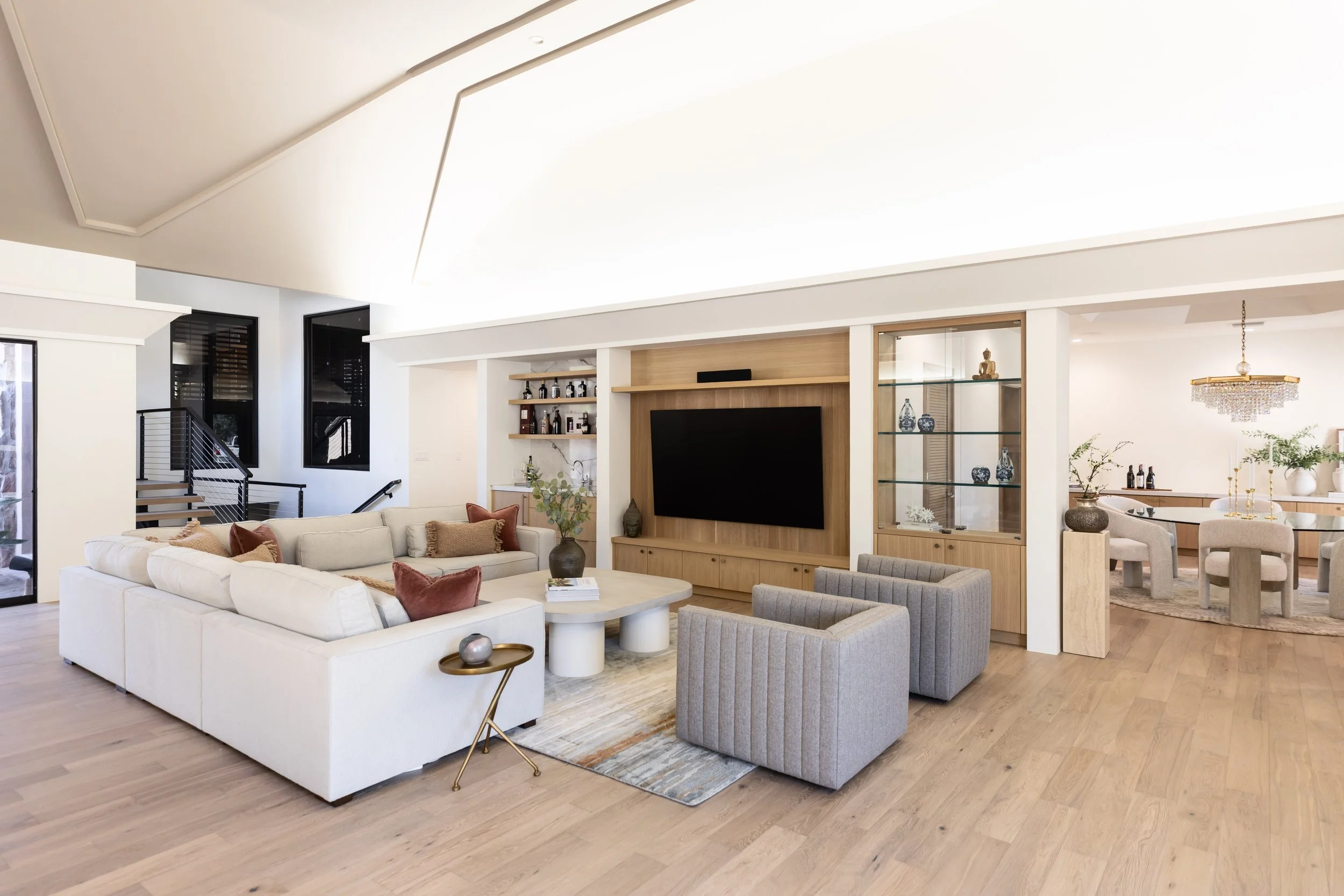 Layered neutral living room furnishings with sculptural tables and integrated custom cabinetry