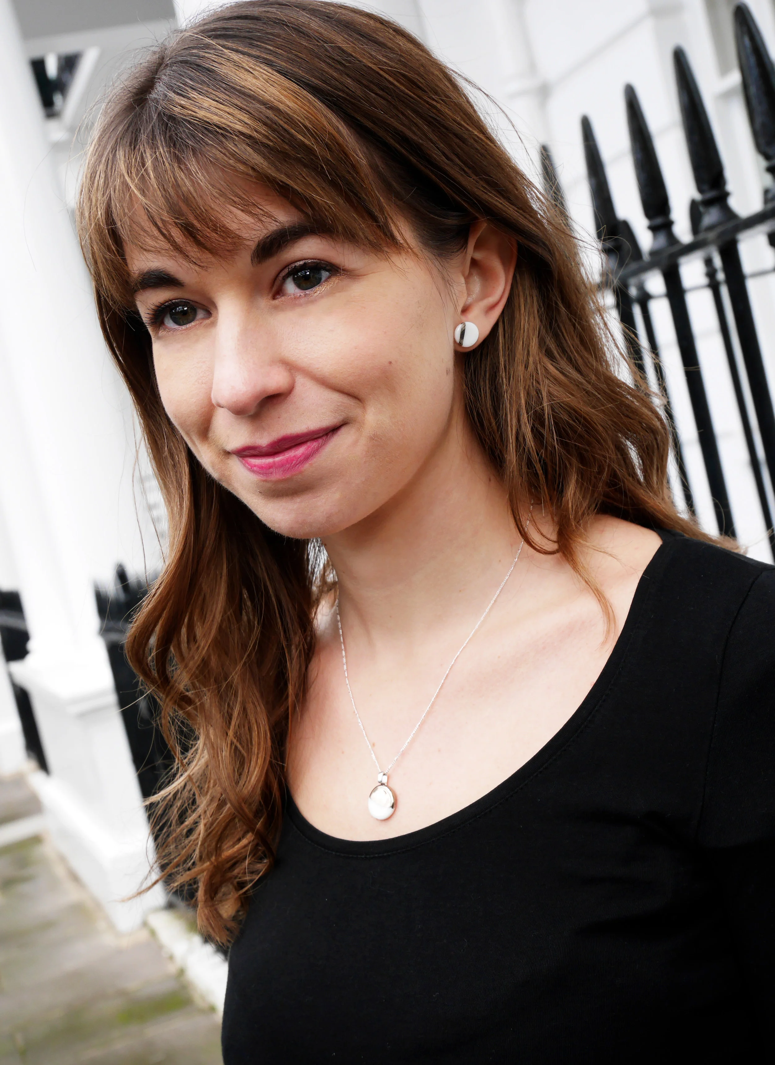 Brunette model wearing ceramic earrings and pendant with platinum lustre