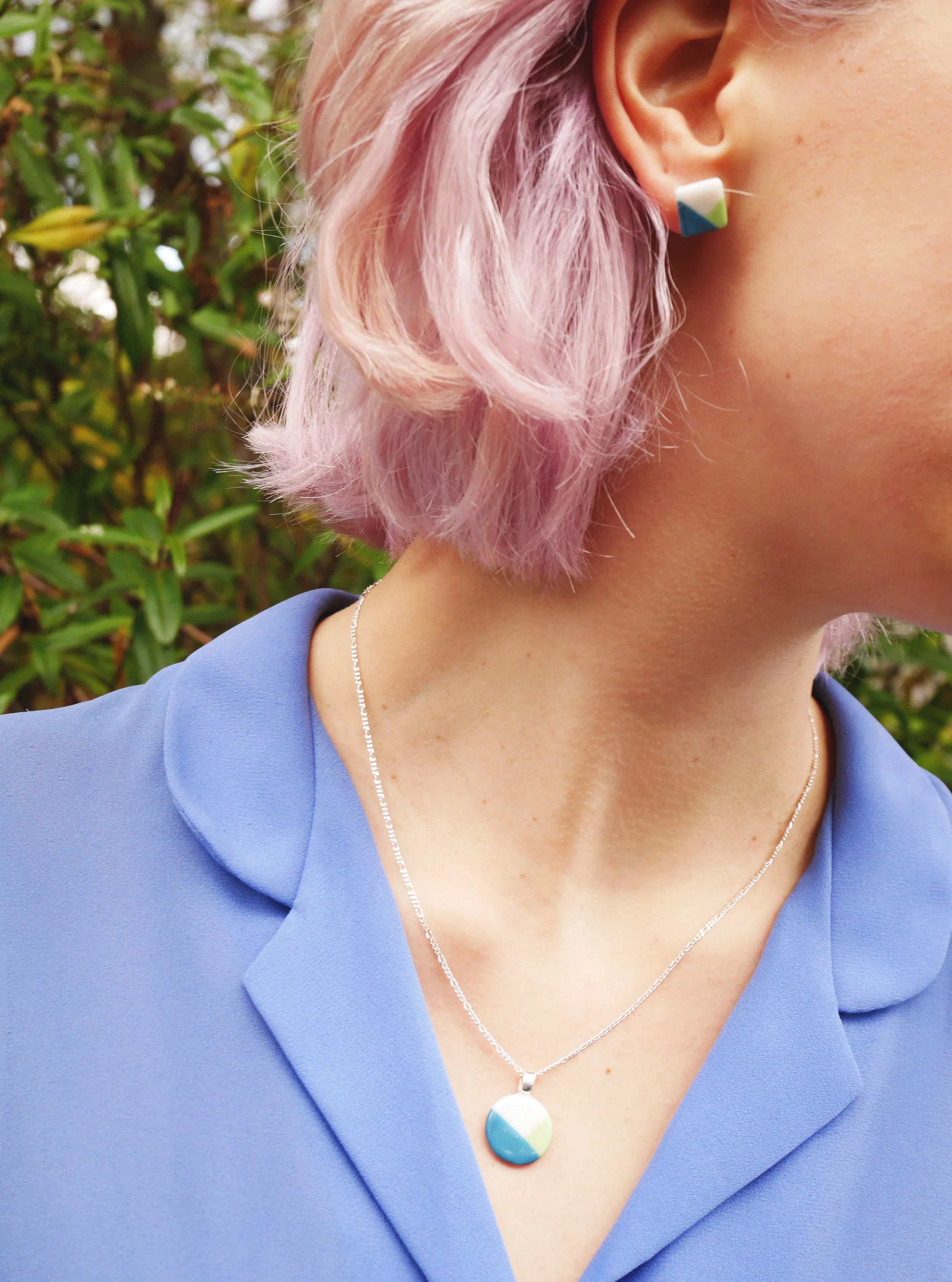 Model with lilac hair wearing geometric earrings and pendant on sterling silver chain
