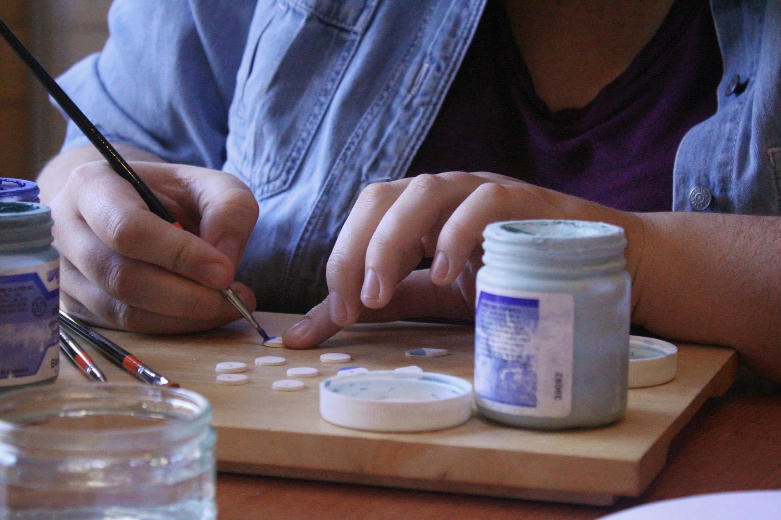 Suzanne hand painting each piece of her ceramic jewellery