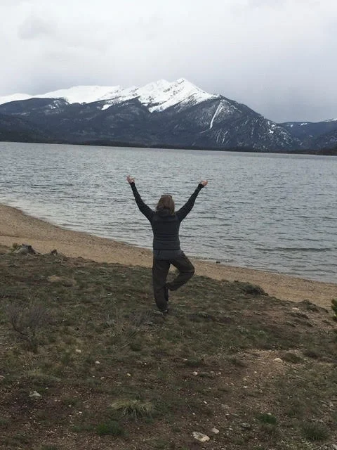 Yoga pose near a lake with mountains in the background
