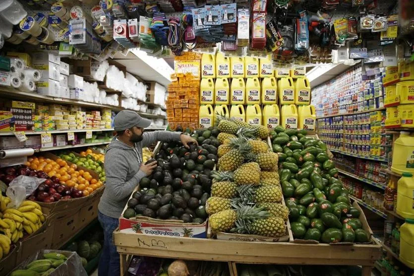 A customer reaches for avocados inside Mello’s Supermarket in Lawrence