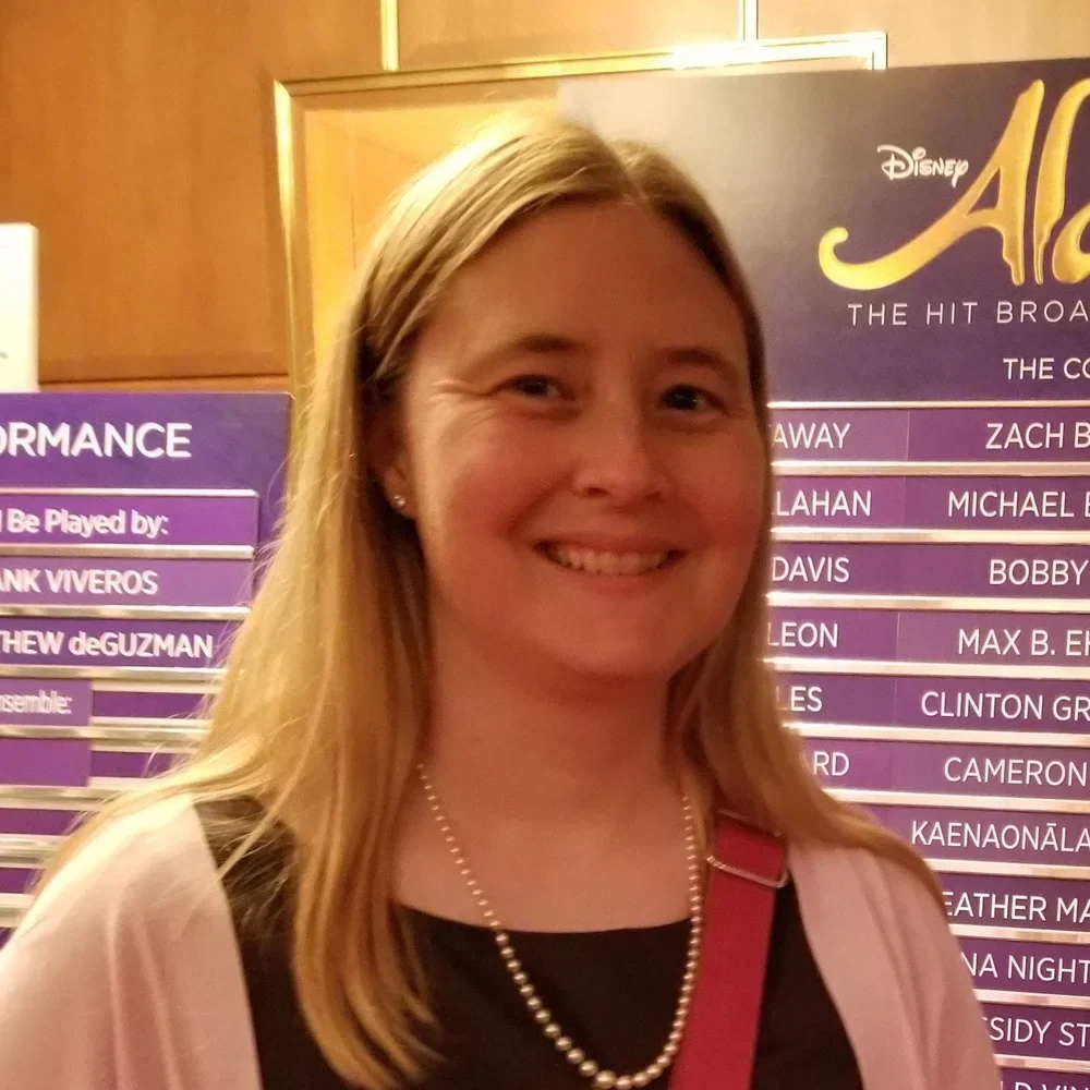 Elizabeth Linsley is smiling at the camera. She is blonde and wearing a pearl necklace.