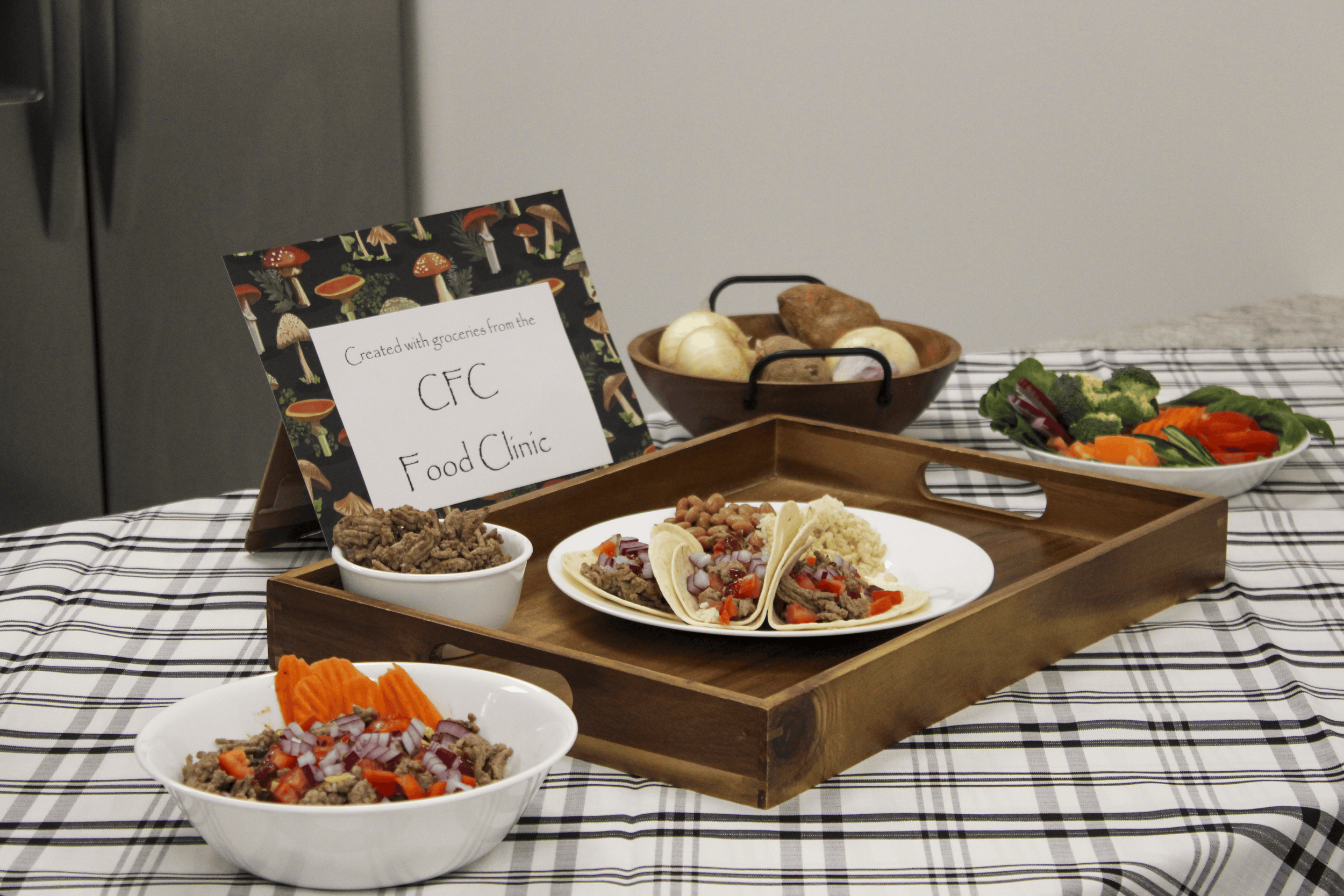 Tacos, rice, beans, and vegetables displayed beside a sign reading “Created with groceries from the CFC Food Clinic.”