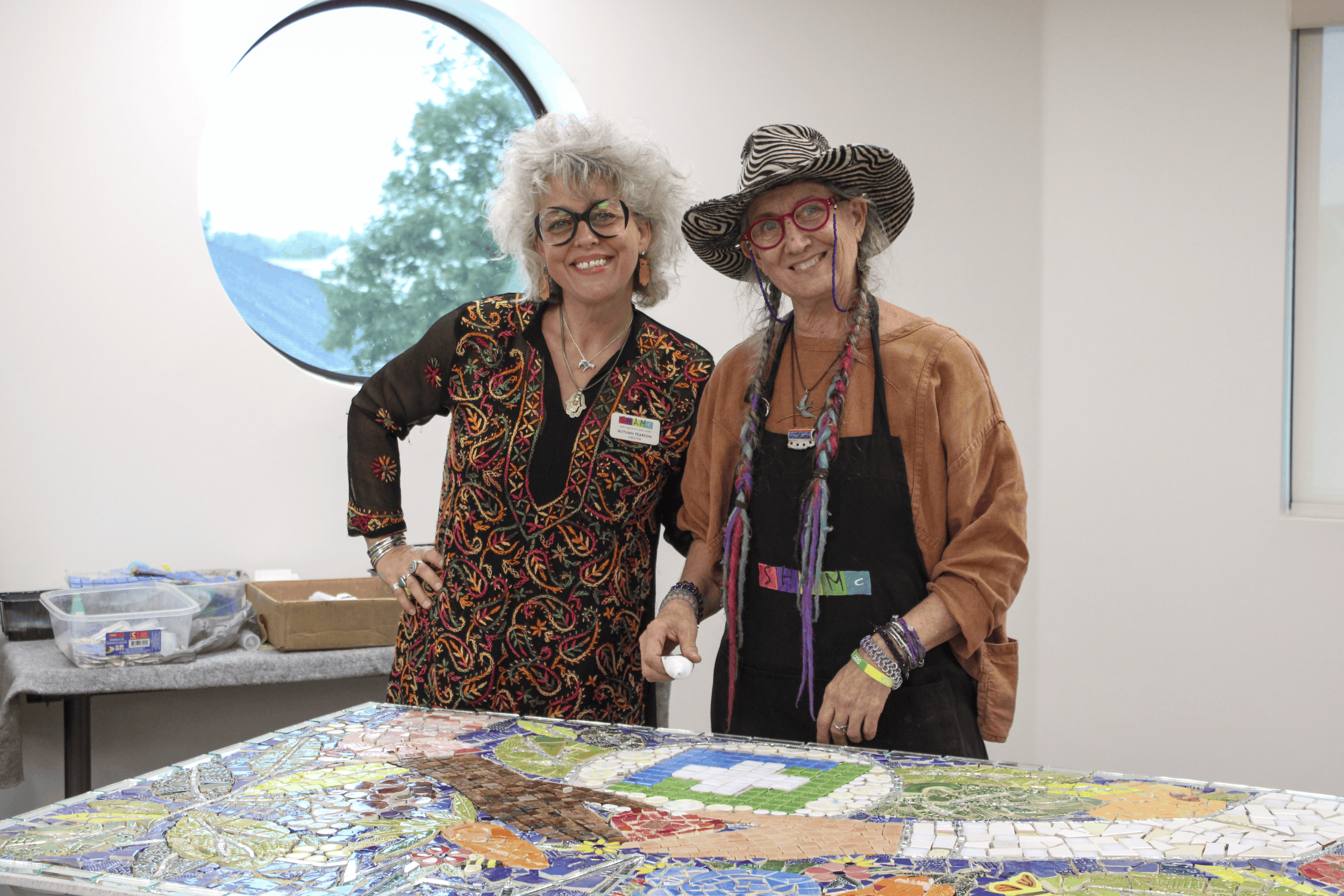 SHAMC stand beside a colorful mosaic artwork inside the Wellness Center.
