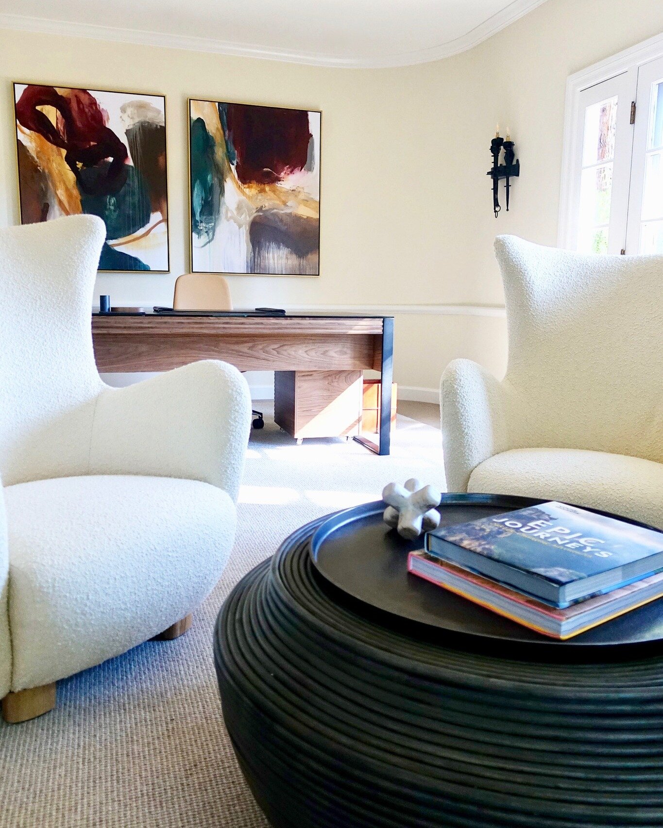 We designed this bright eclectic office complete with a casual sitting area. We added some ivory Boucle chairs from CB2 which are a modern version of the wing chair. The contrasting dark stained coffee table and abstract art bring in texture and colo